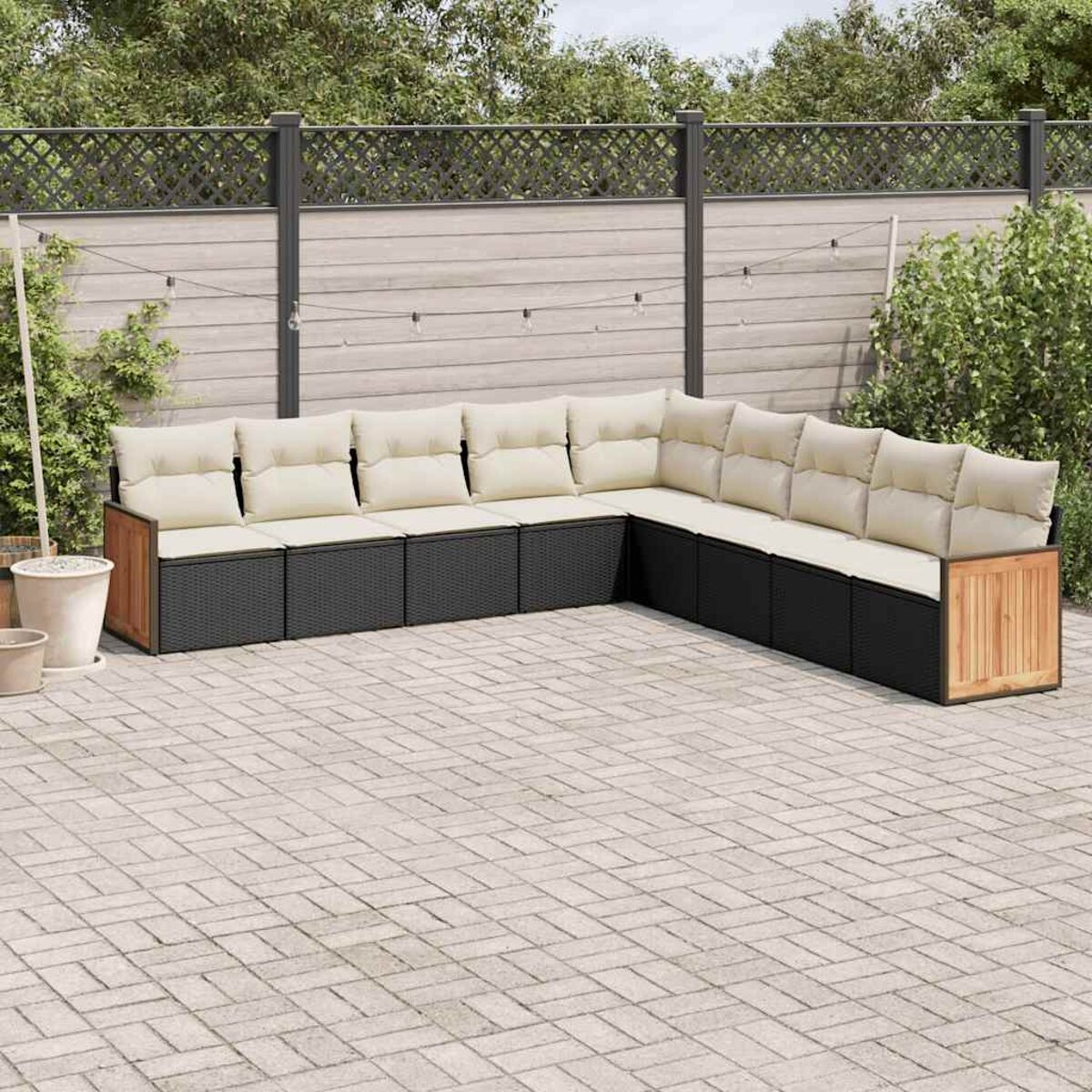Outdoor-Ecksofa mit beigen Kissen. Es ist aus schwarzem Korbgeflecht mit Holzakzenten.