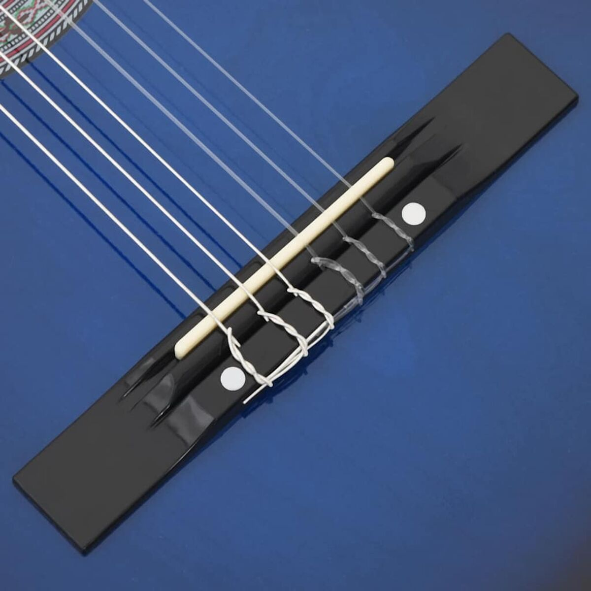 Nahaufnahme der Gitarrenbrücke. Blauer Korpus, schwarze Brücke, weiße Saiten und Stifte, hölzerner Sattel.