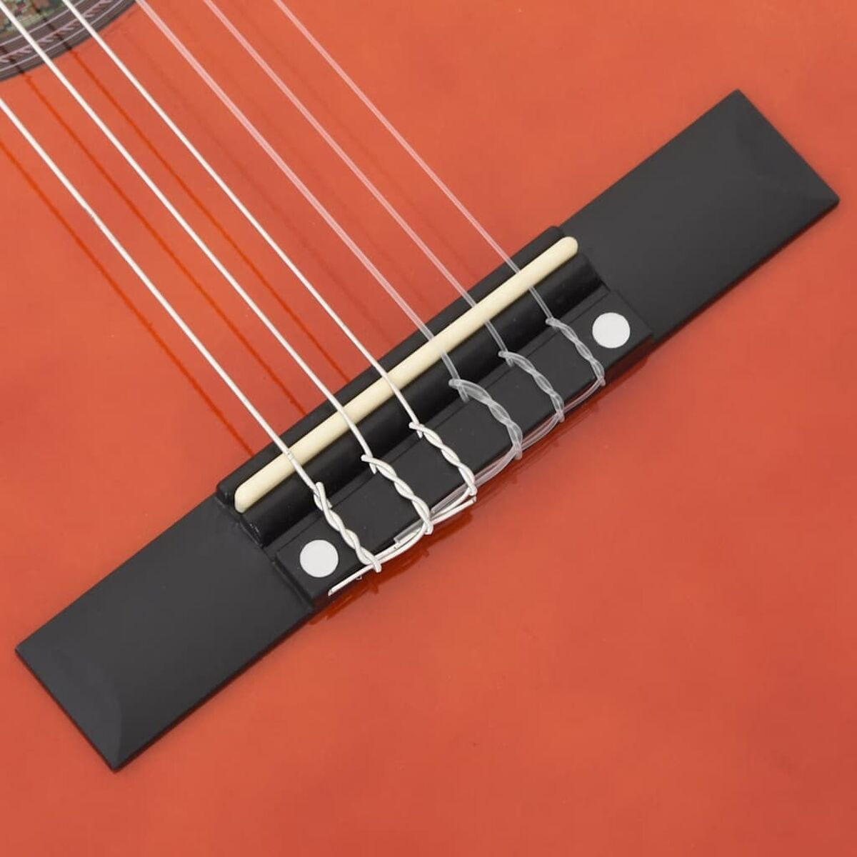 Nahaufnahme eines Gitarrenstegs mit Saiten. Die Gitarre ist rot. Die Saiten sind weiß.