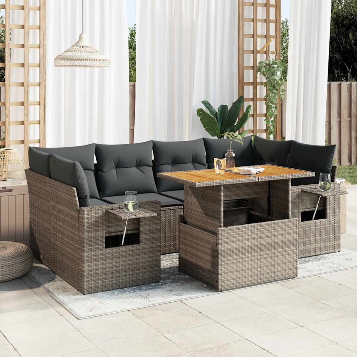 Set divani in vimini da esterno con cuscini, tavolino e sfondo bianco.