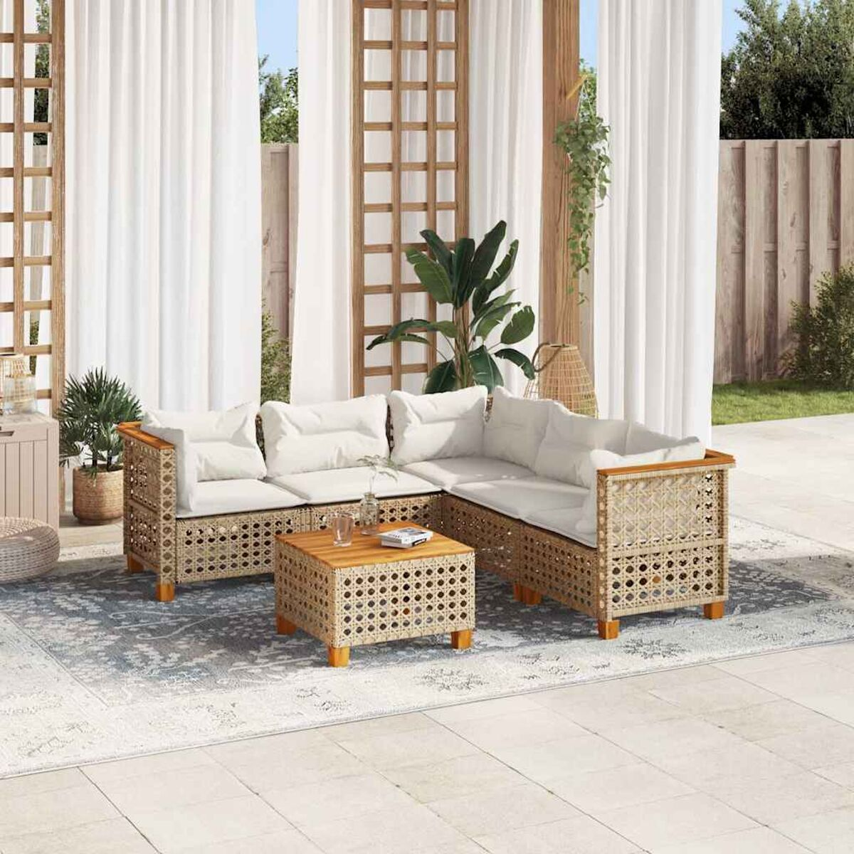 Set di mobili da esterno in rattan con tavolo e sedute, più elementi decorativi.