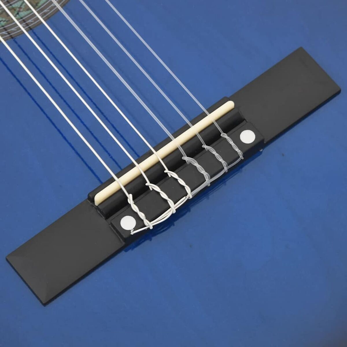Nahaufnahme des Gitarrenstegs mit Saiten und schwarzem Hintergrund.