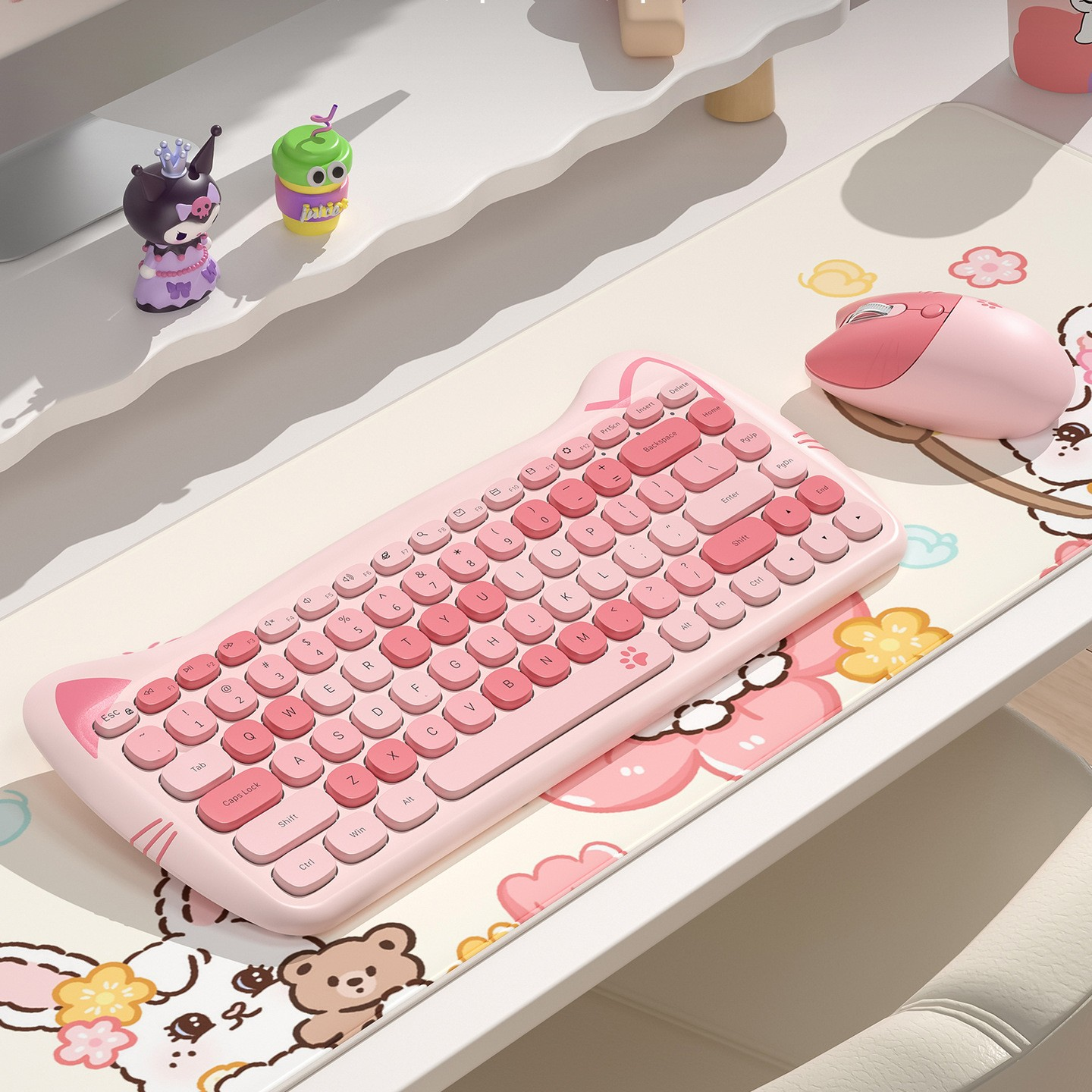 Rosa Tastatur und Maus auf einem Schreibtisch, mit Dekorationen und kleinen Spielfiguren.