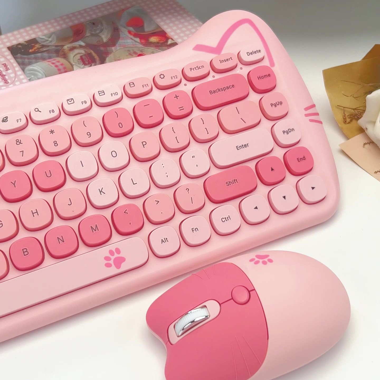 Rosa Tastatur und Maus im Katzen-Design auf weißer Oberfläche. Die Tastatur hat Katzenohren.