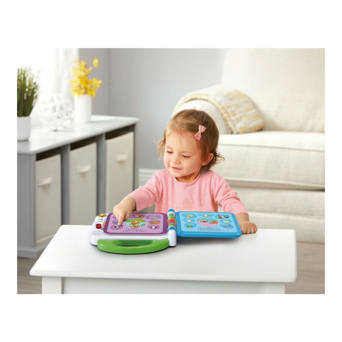 Un bambino piccolo seduto a un tavolo interagisce con un libro di apprendimento elettronico colorato.