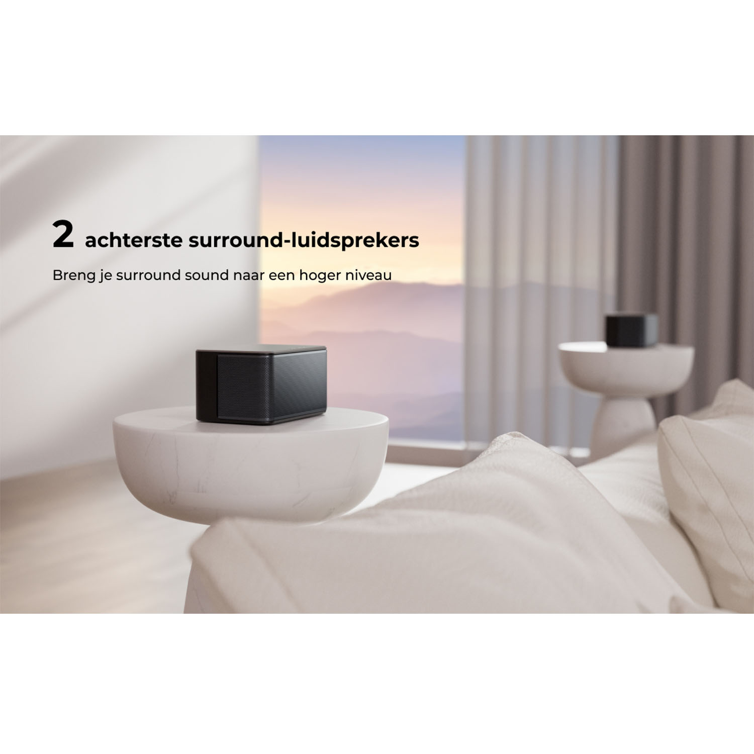 Un haut-parleur noir sur une table blanche, un haut-parleur noir en arrière-plan. Des coussins moelleux sont présents.