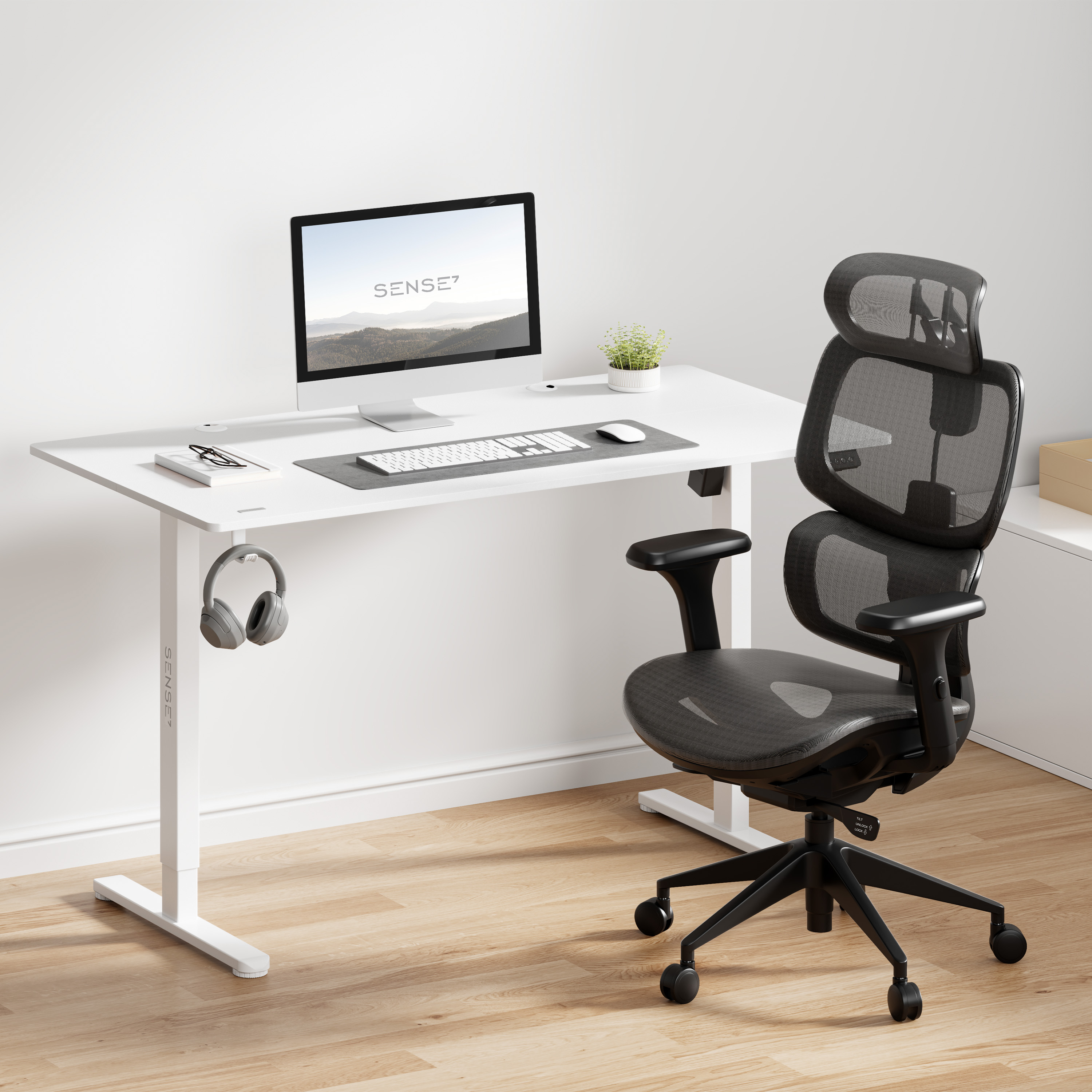 Een witte bureau met een computer, toetsenbord, muis en koptelefoon.