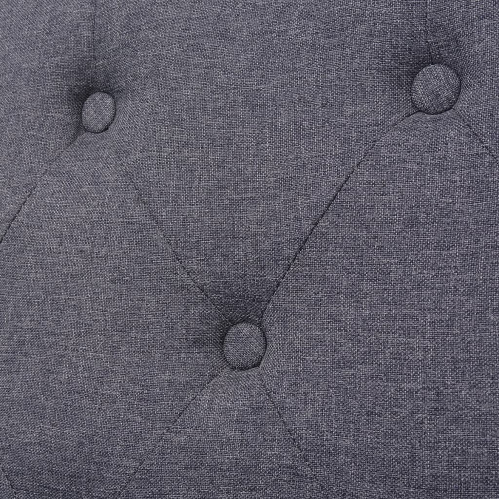 Nahaufnahme eines grauen Stoffes mit Rautenmuster und drei sichtbaren Knöpfen.