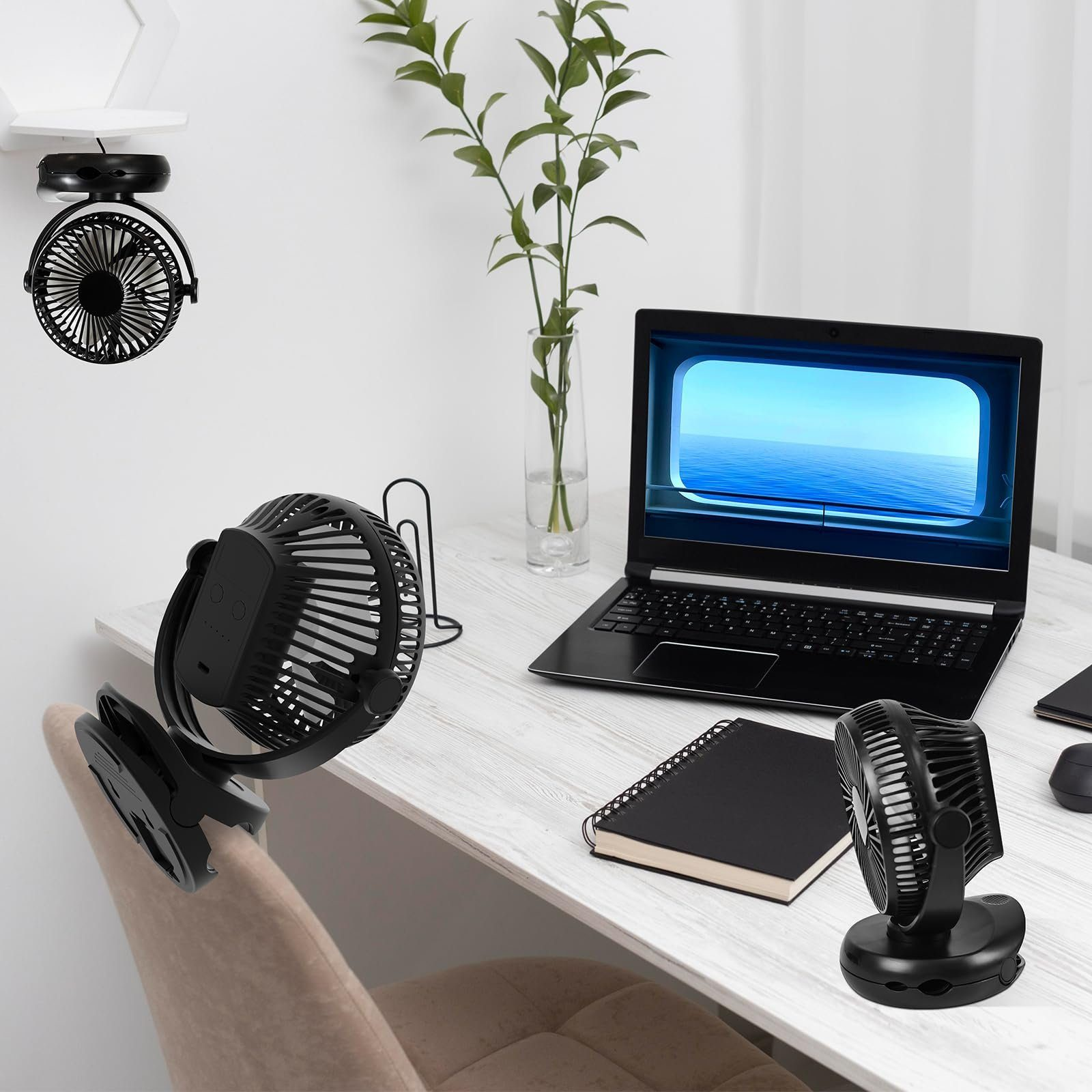 Biurko z laptopem, notatnikiem i trzema czarnymi wentylatorami. Roślina w tle.
