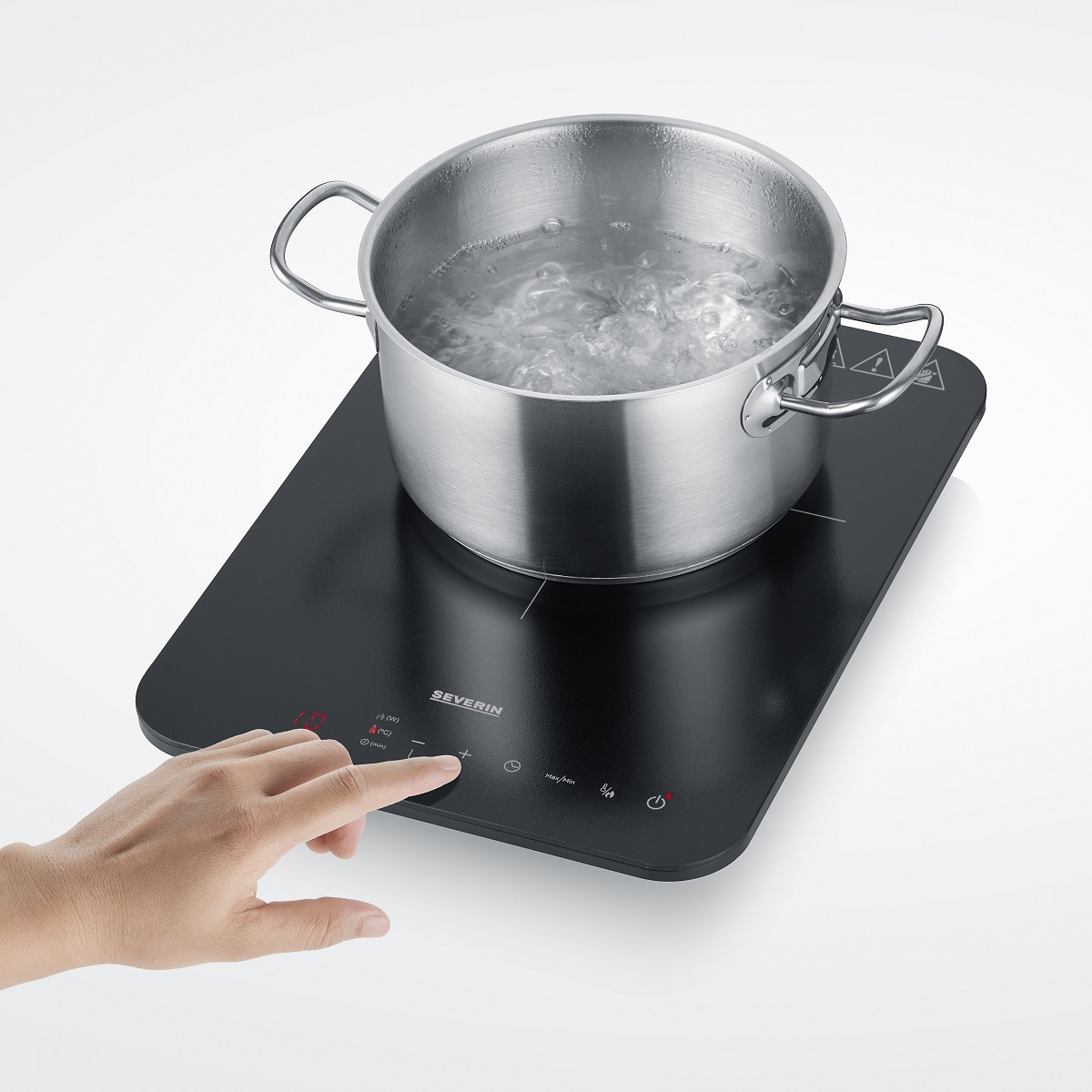 Garnek z wrzącą wodą na czarnej płycie indukcyjnej.