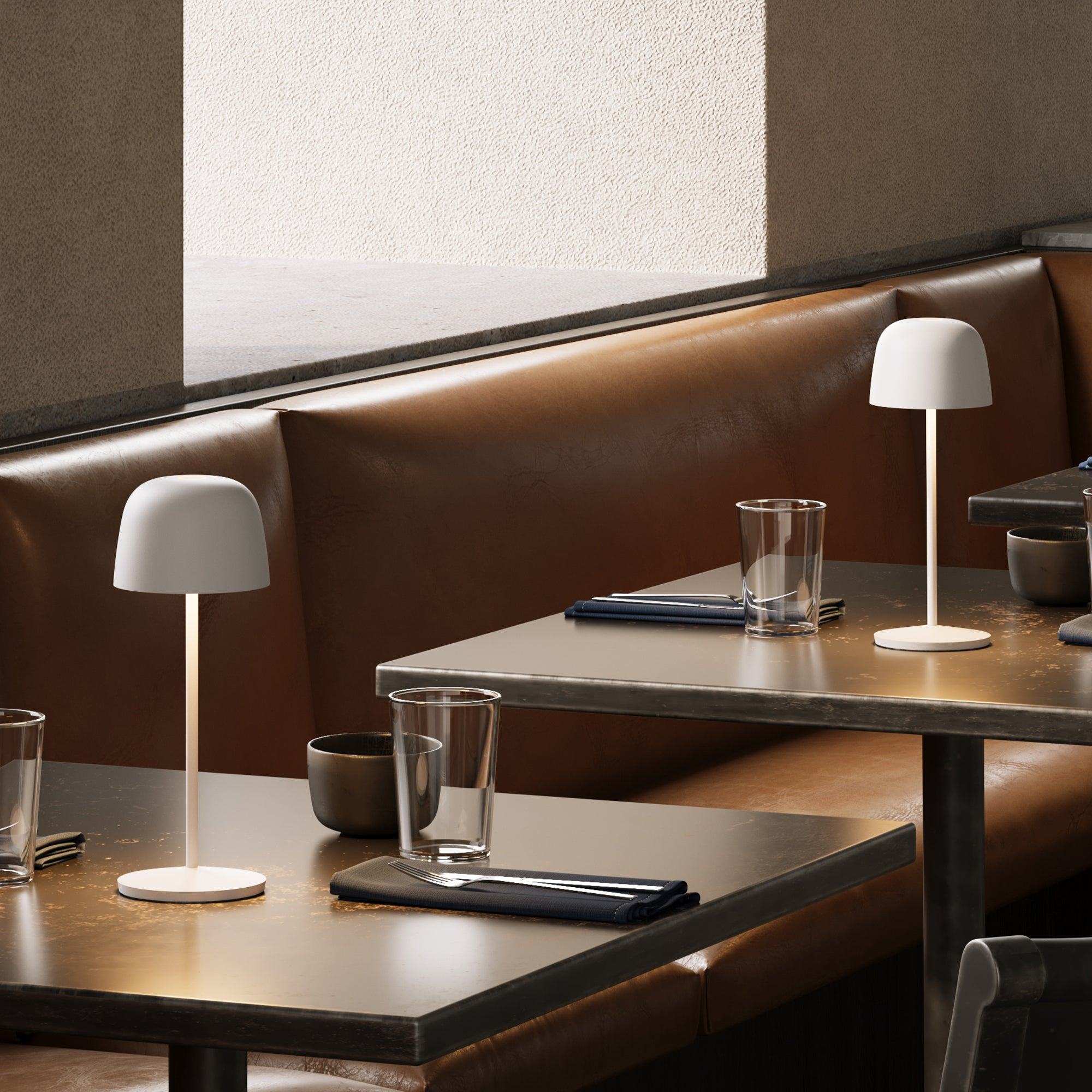 Restaurant mit Tischen, Lampen, Gläsern und brauner Lederbank.