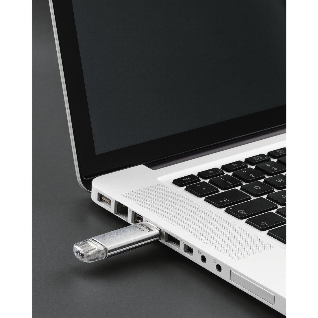 Srebrny pendrive włożony do laptopa, z czarnym ekranem.