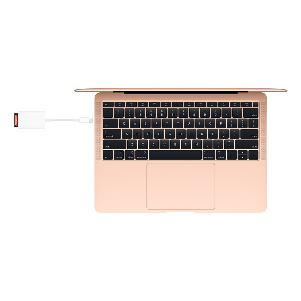Laptop mit USB-C-Adapter, der mit einem USB-Laufwerk verbunden ist, auf weißer Oberfläche.