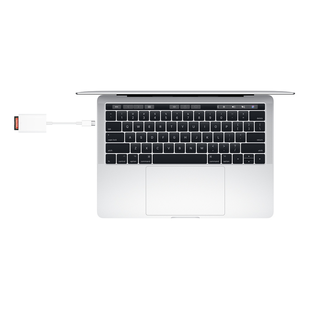 Laptop mit USB-C-Adapter, der mit einem USB-Laufwerk verbunden ist, auf weißer Oberfläche.