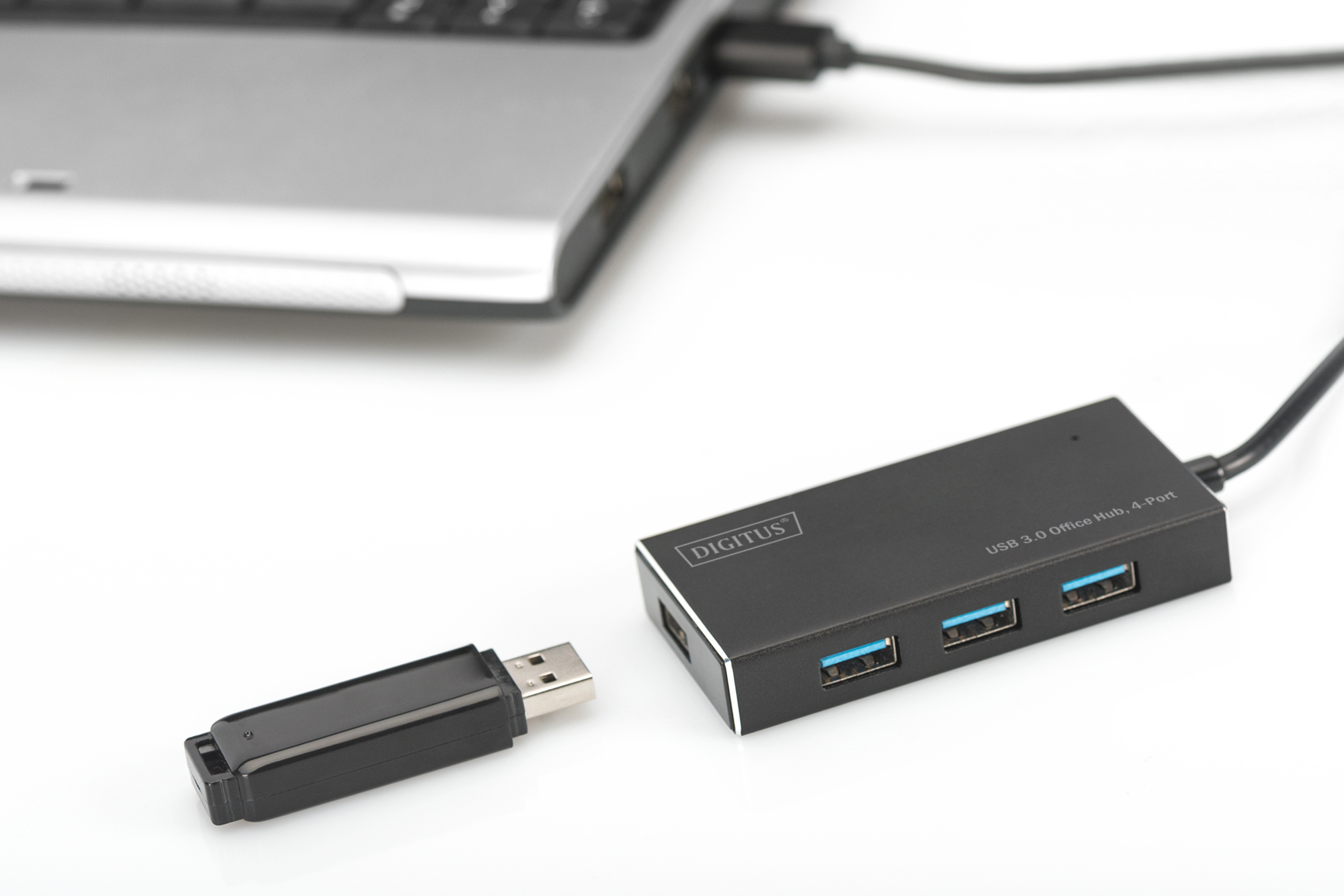 USB 3.0 Hub neben einem Laptop und einem USB-Stick, alles auf weißem Untergrund.