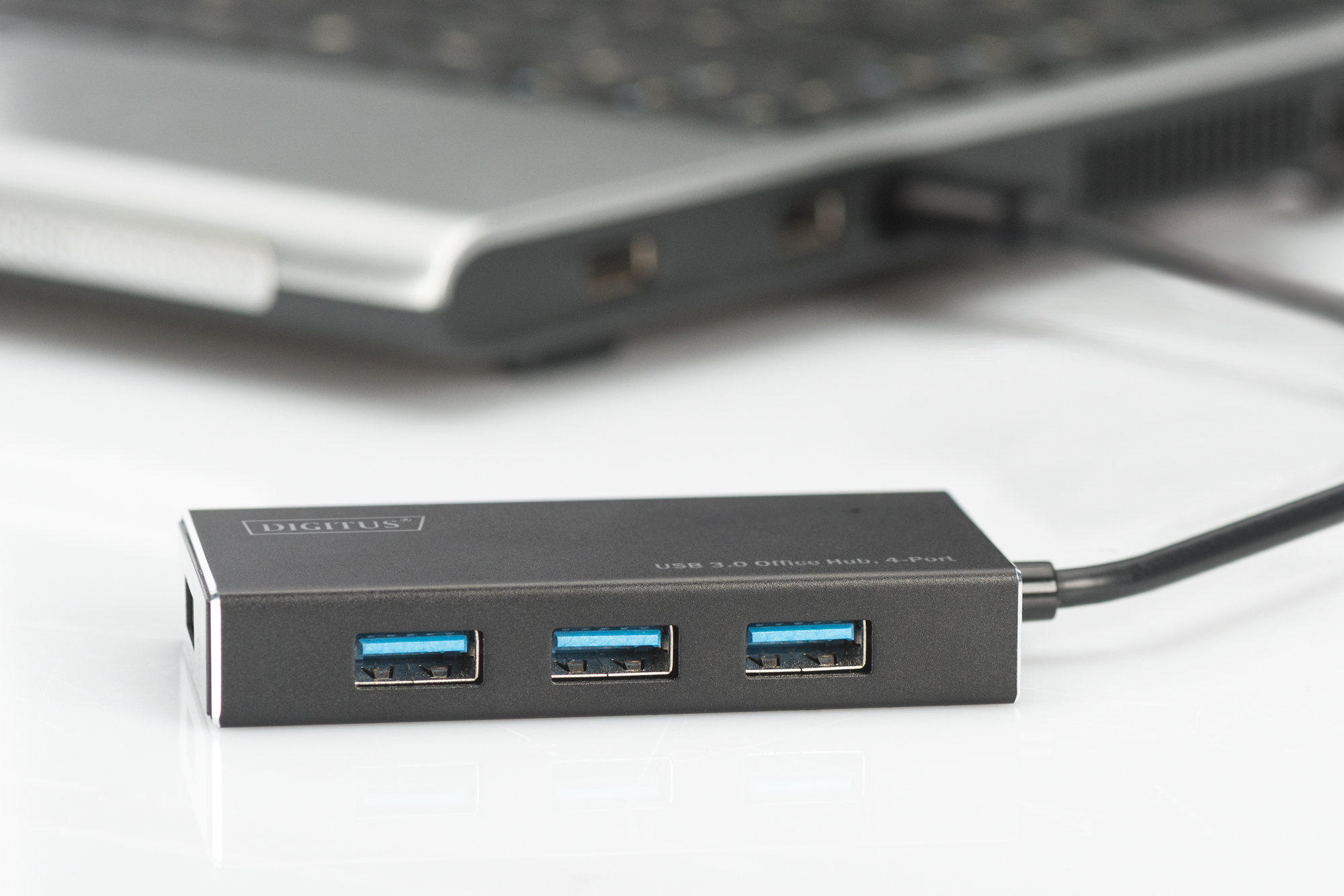 Schwarzer USB 3.0 Hub an einen Laptop angeschlossen. Drei blaue USB-Anschlüsse sichtbar.