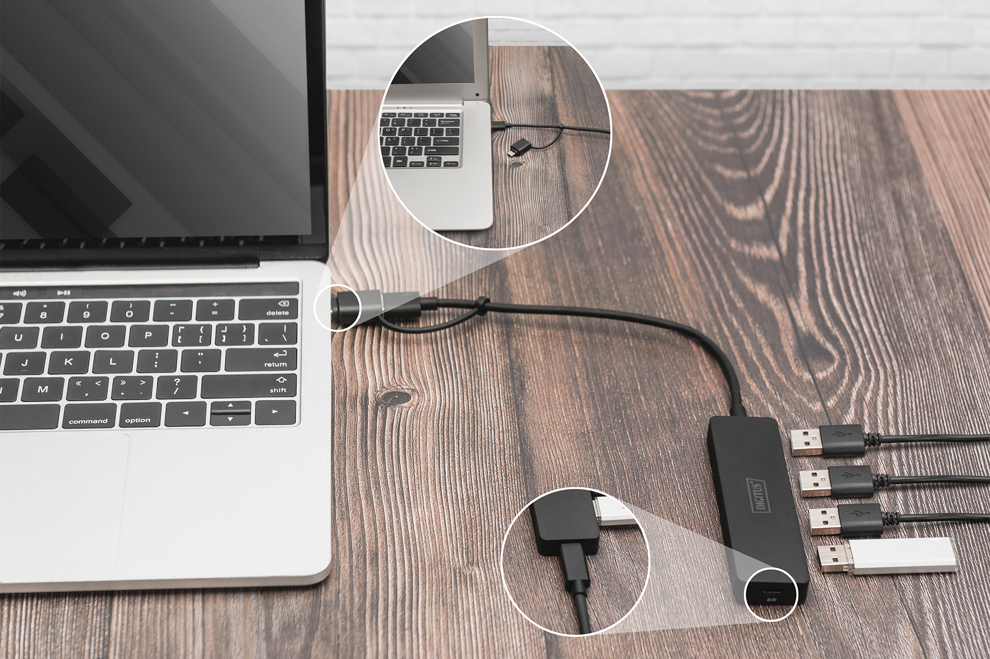 Laptop collegato a un hub USB su una scrivania di legno. Vari cavi USB collegati.