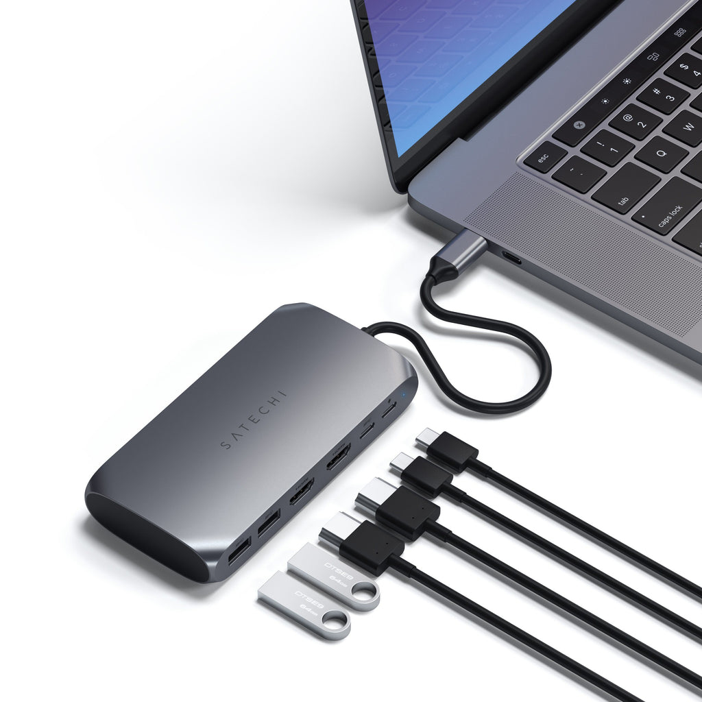 Laptop collegato a un adattatore multi-porta con unità USB e cavi.