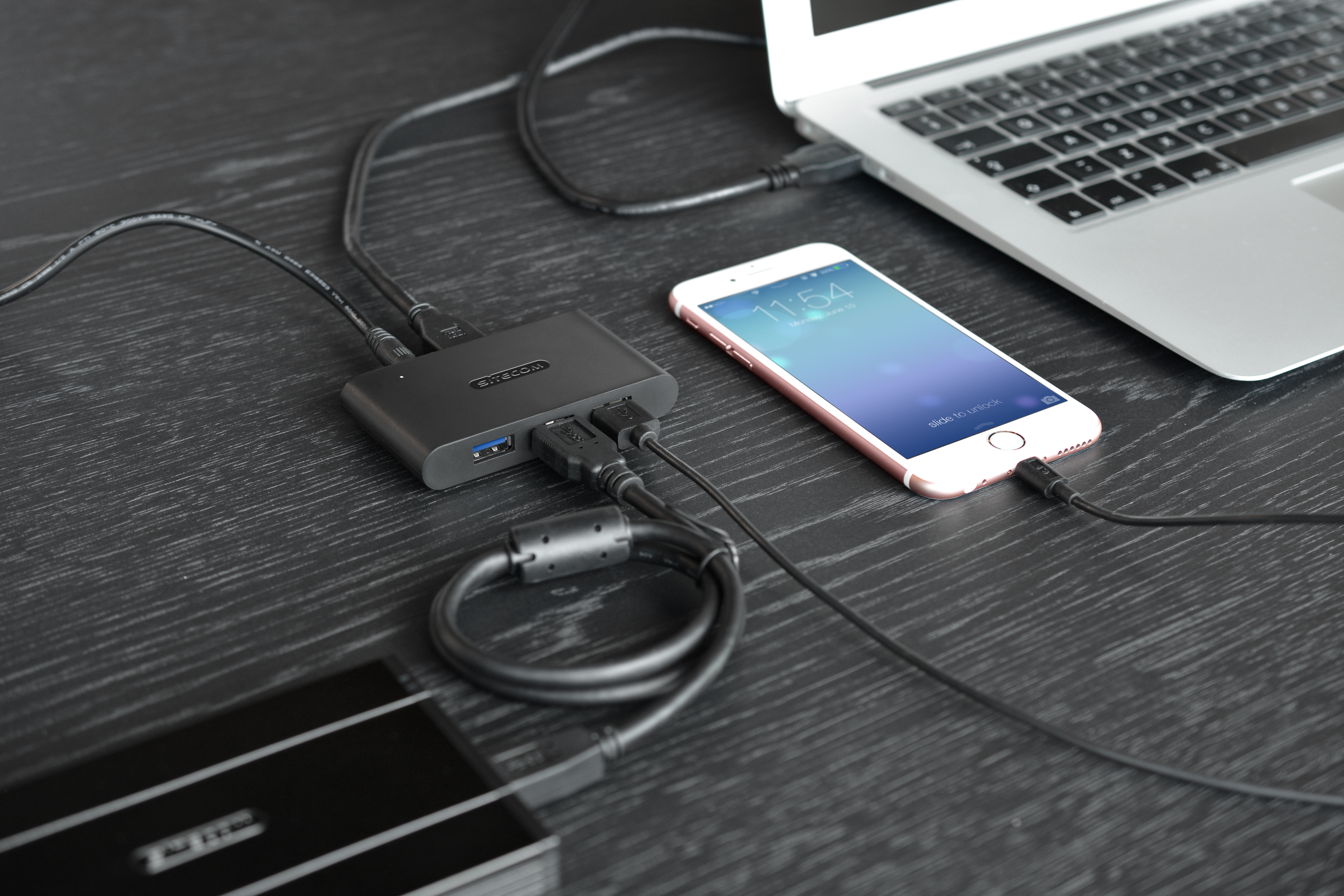 Hub USB nero collegato a laptop, telefono e disco rigido esterno.