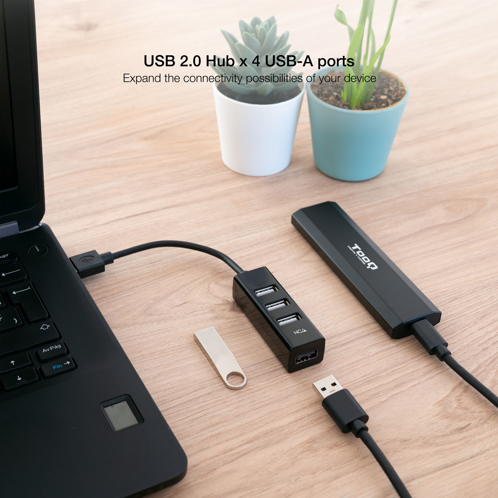 Un concentrador USB con un portátil, una unidad USB y otros cables USB sobre una superficie de madera.