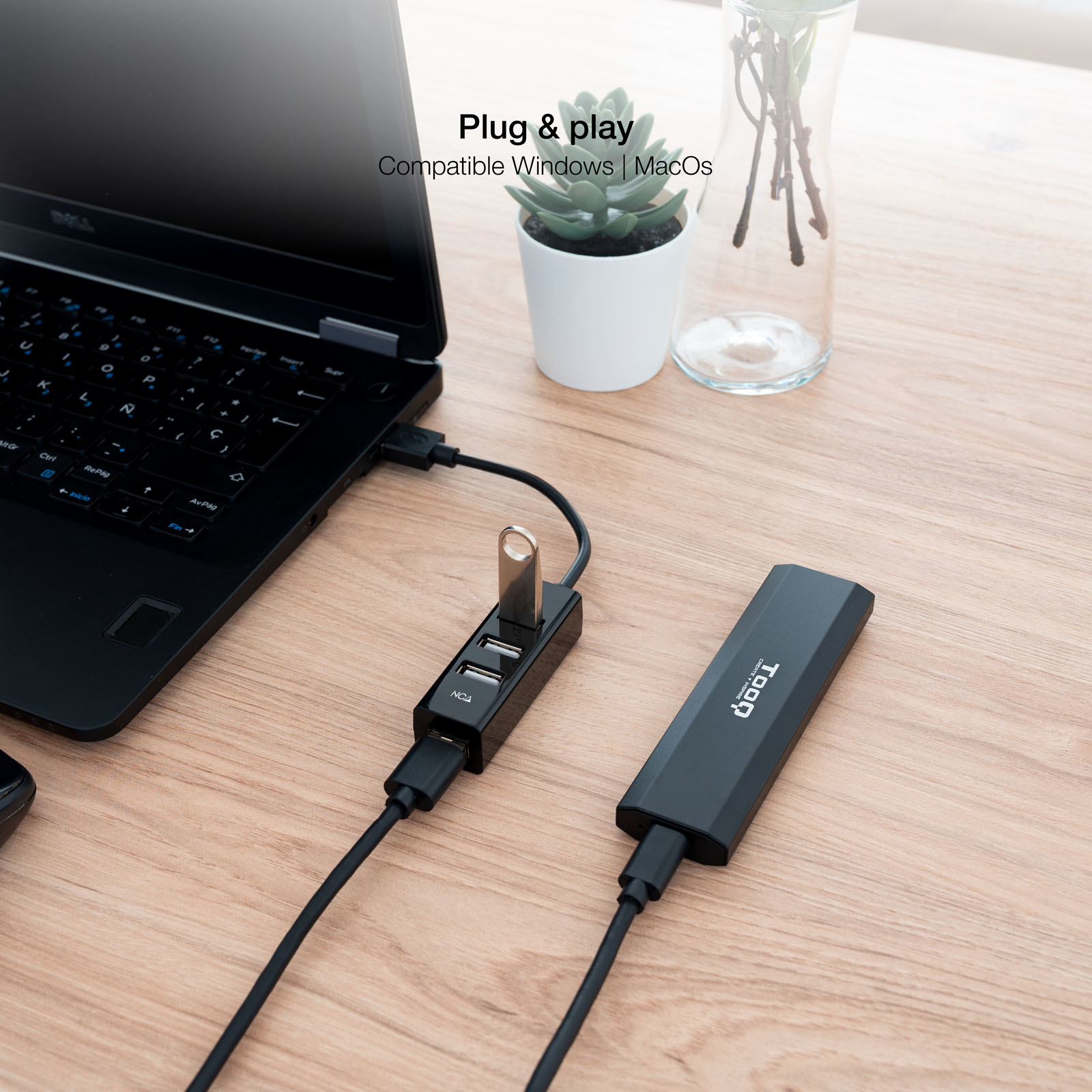 Concentrador USB conectado a un portátil. El concentrador tiene 4 puertos USB. Portátil, pendrive y planta.