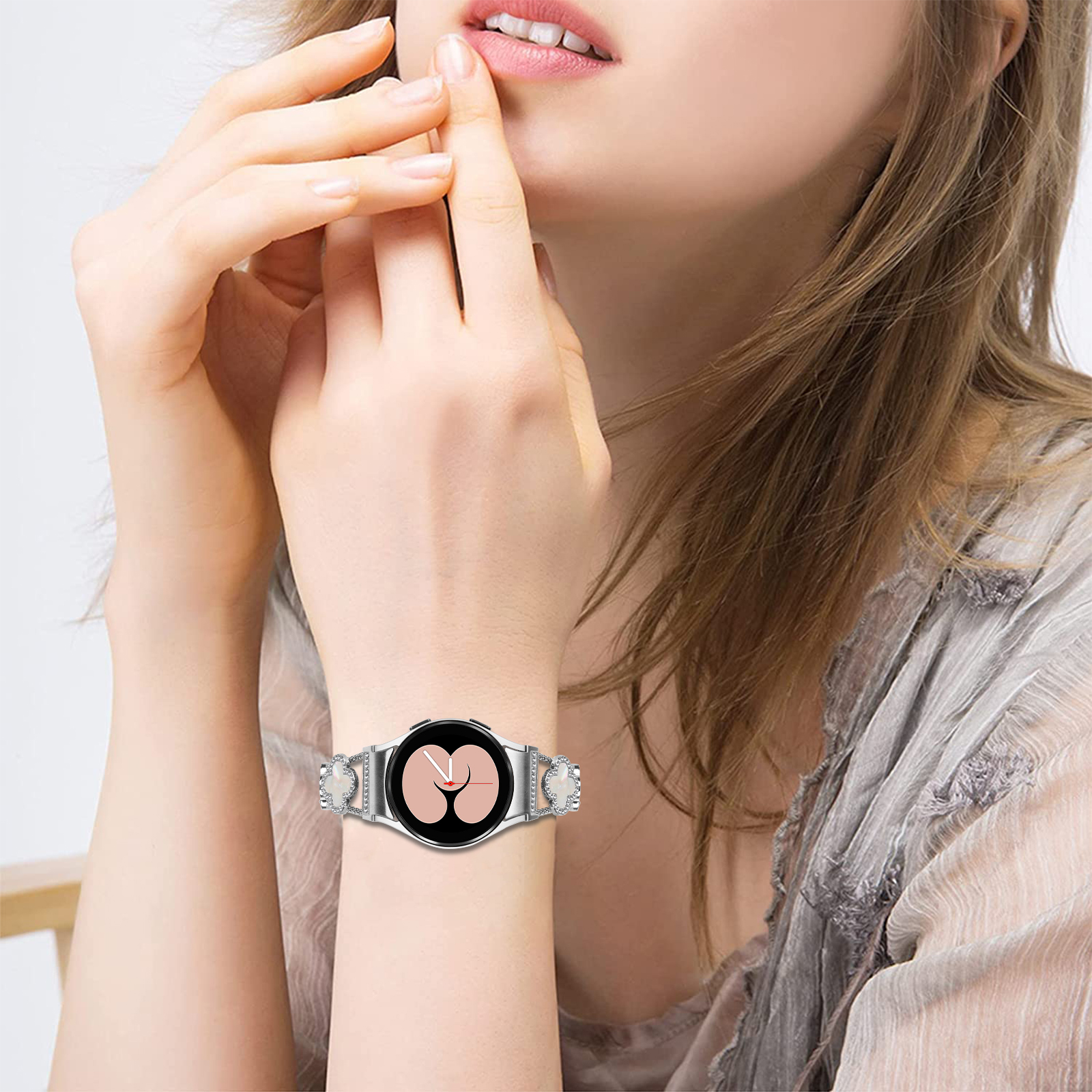 Nahaufnahme des Handgelenks einer Frau mit einer silbernen Smartwatch und rosa Display.