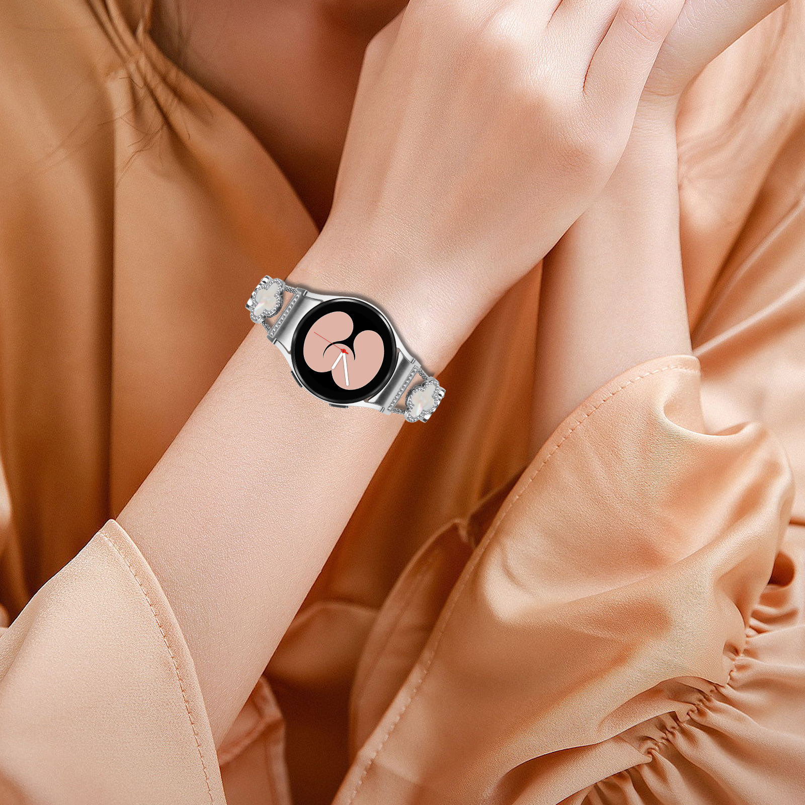 Das Handgelenk einer Frau, die eine silberne Smartwatch mit herzförmigem Display trägt.