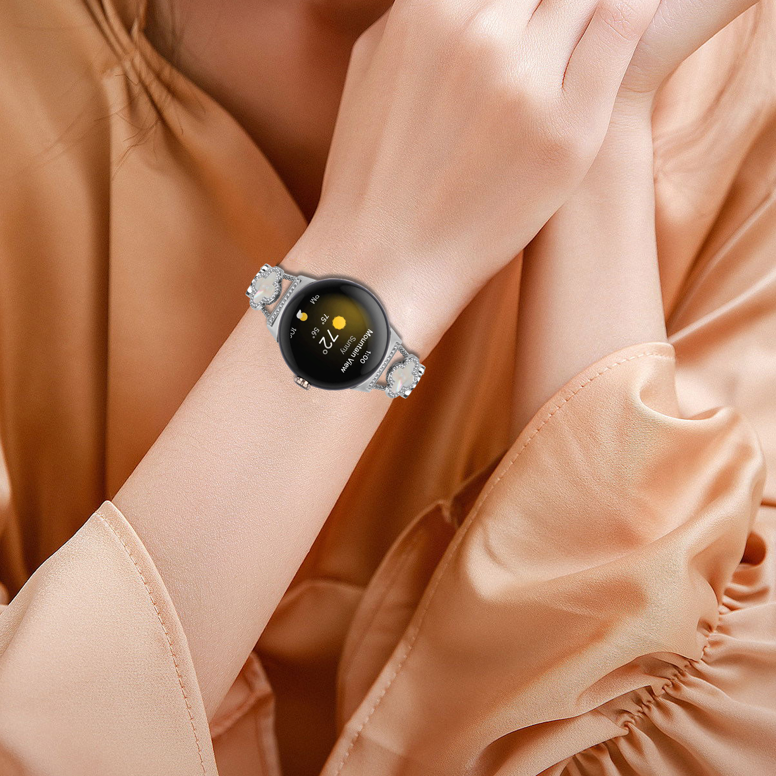 Polso di una donna con smartwatch che mostra l'ora e il meteo. Abbigliamento color oro.