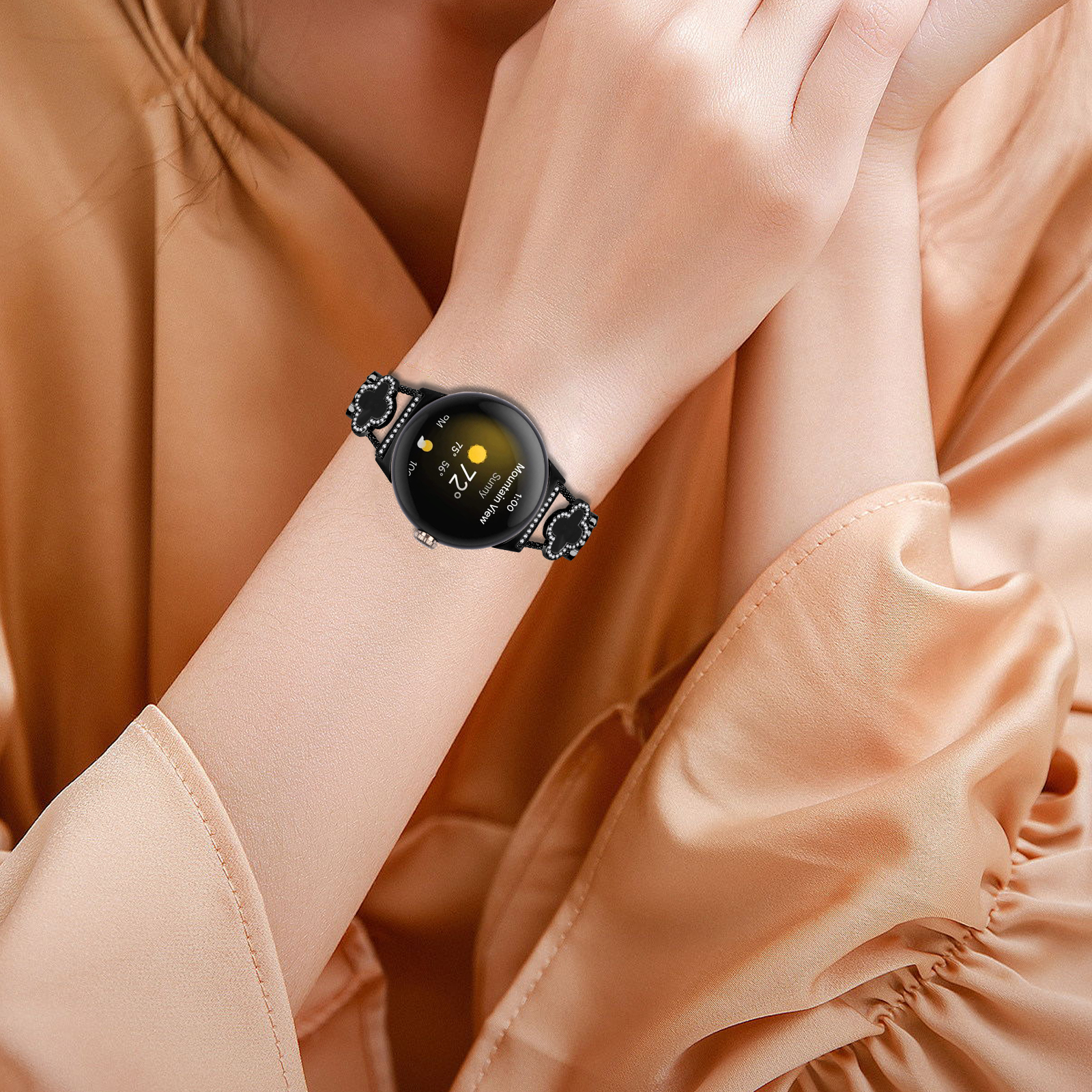 Polso con smartwatch nero. L'orologio ha un cinturino floreale nero e mostra ora e meteo.