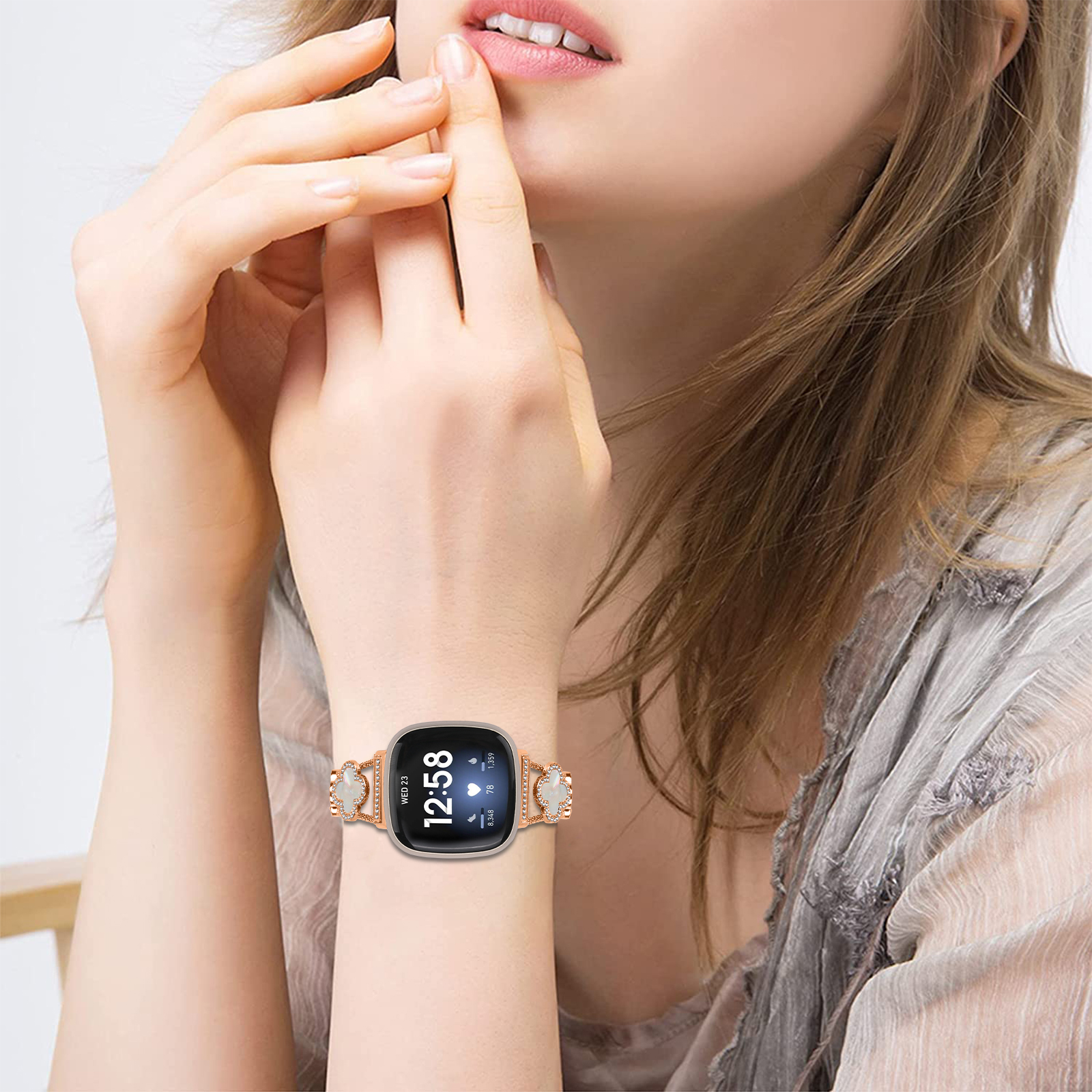 Eine Frau, die eine Uhr trägt. Die Uhr ist goldfarben mit weißem Zifferblatt und goldenem Armband.
