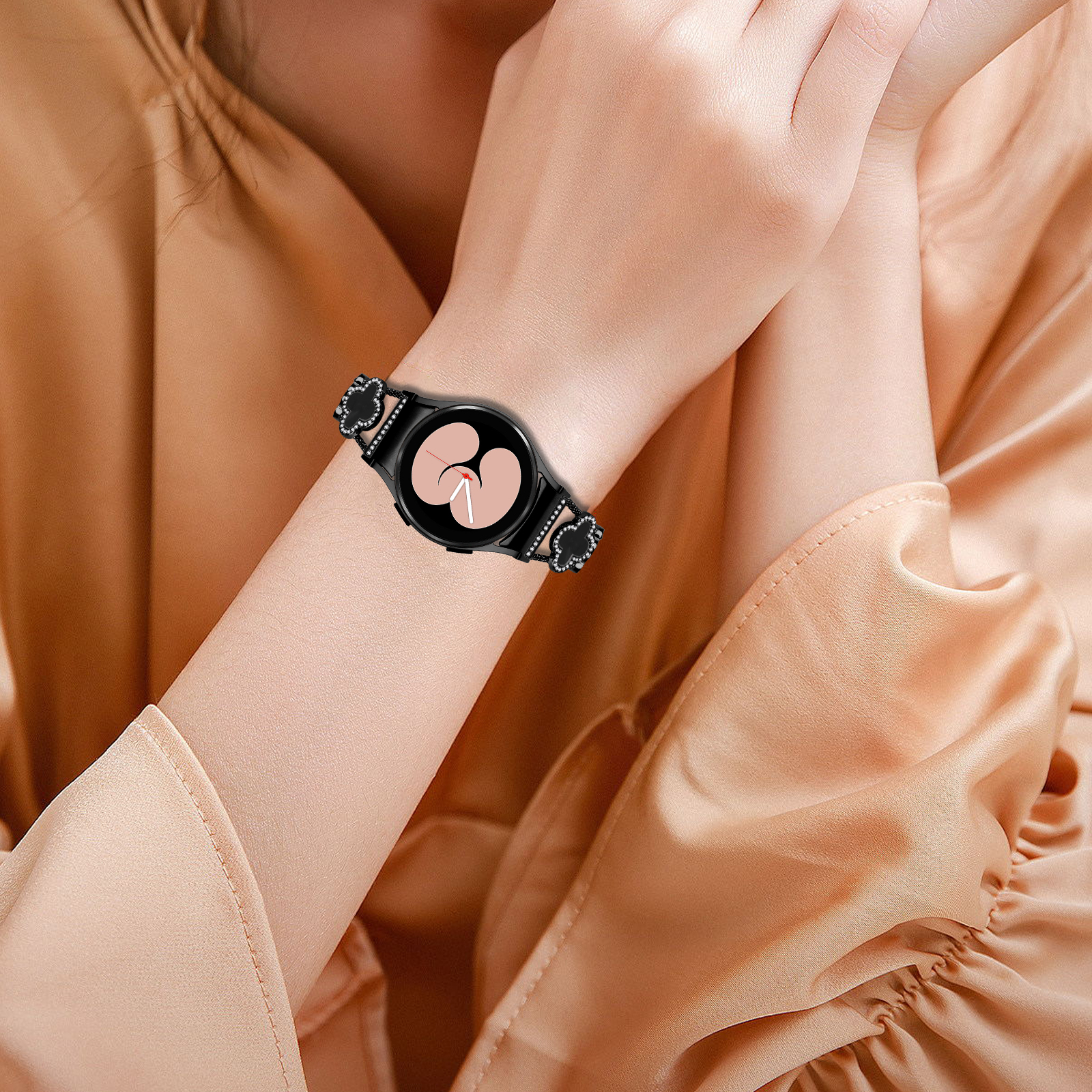 Das Handgelenk einer Frau mit schwarzer Smartwatch und einem schwarzen, edelsteinbesetzten Armband.
