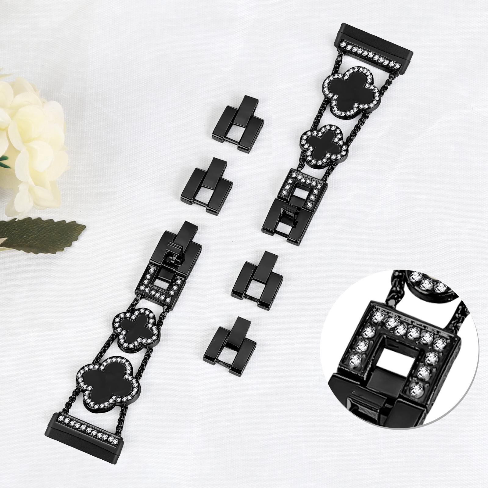 Schwarzes Uhrenarmband mit Kleeblatt-Designs und kleinen Edelsteinen. Abgetrennte Verbinder sichtbar.