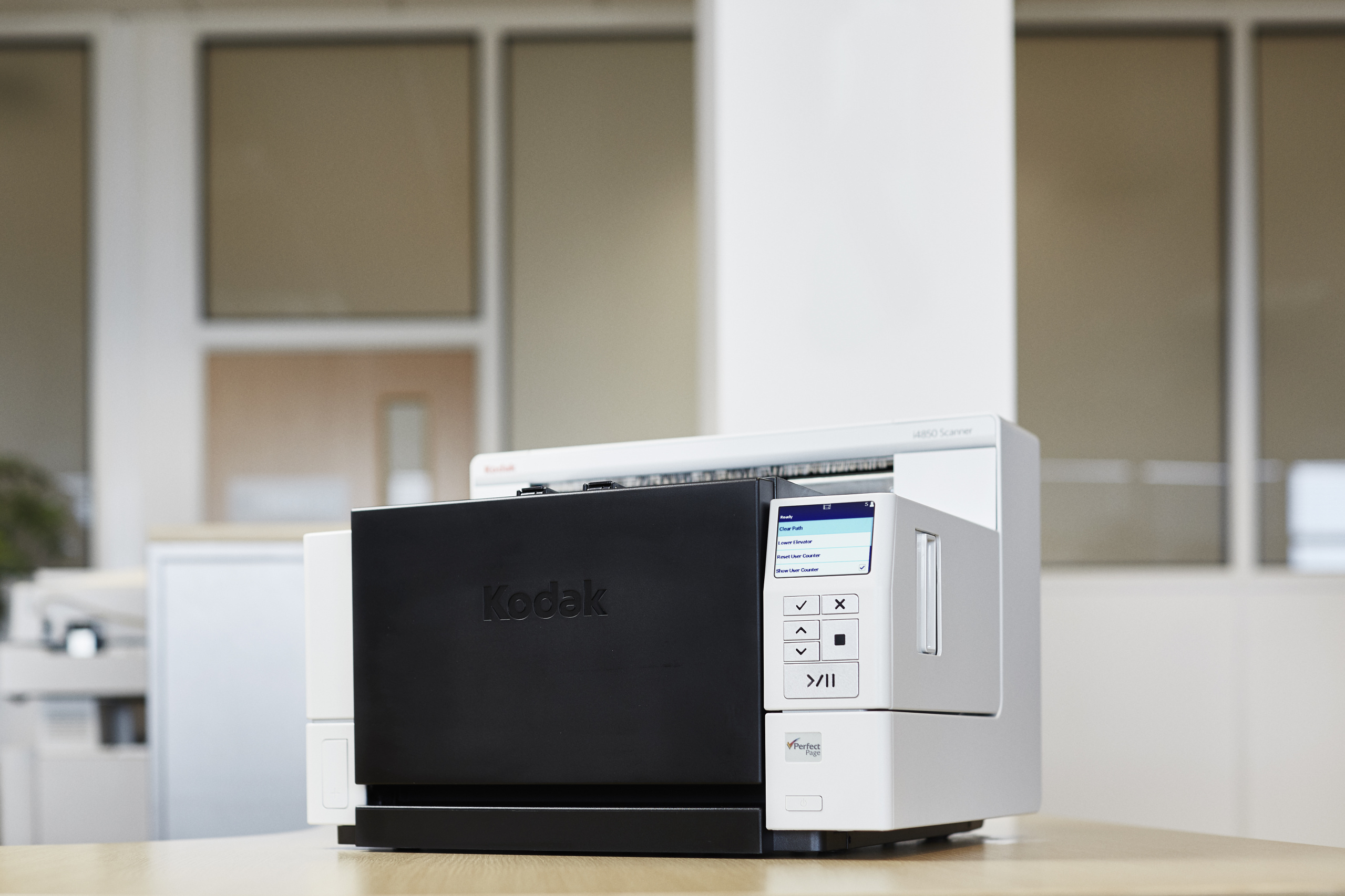 Ein Kodak-Drucker auf einem Tisch. Vorne befindet sich eine schwarze Bedienblende, mit weißem Hintergrund.