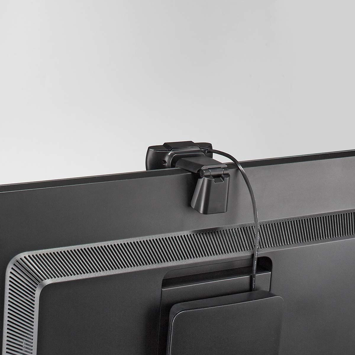 Una webcam nera collegata a una TV nera, cavo visibile.