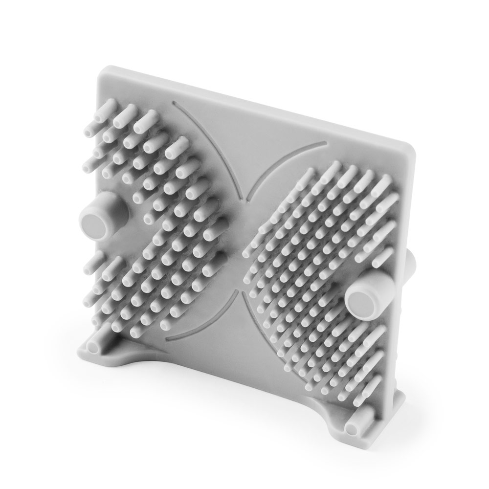 Szary masażer do stóp z wieloma małymi szpilkami. Białe tło.