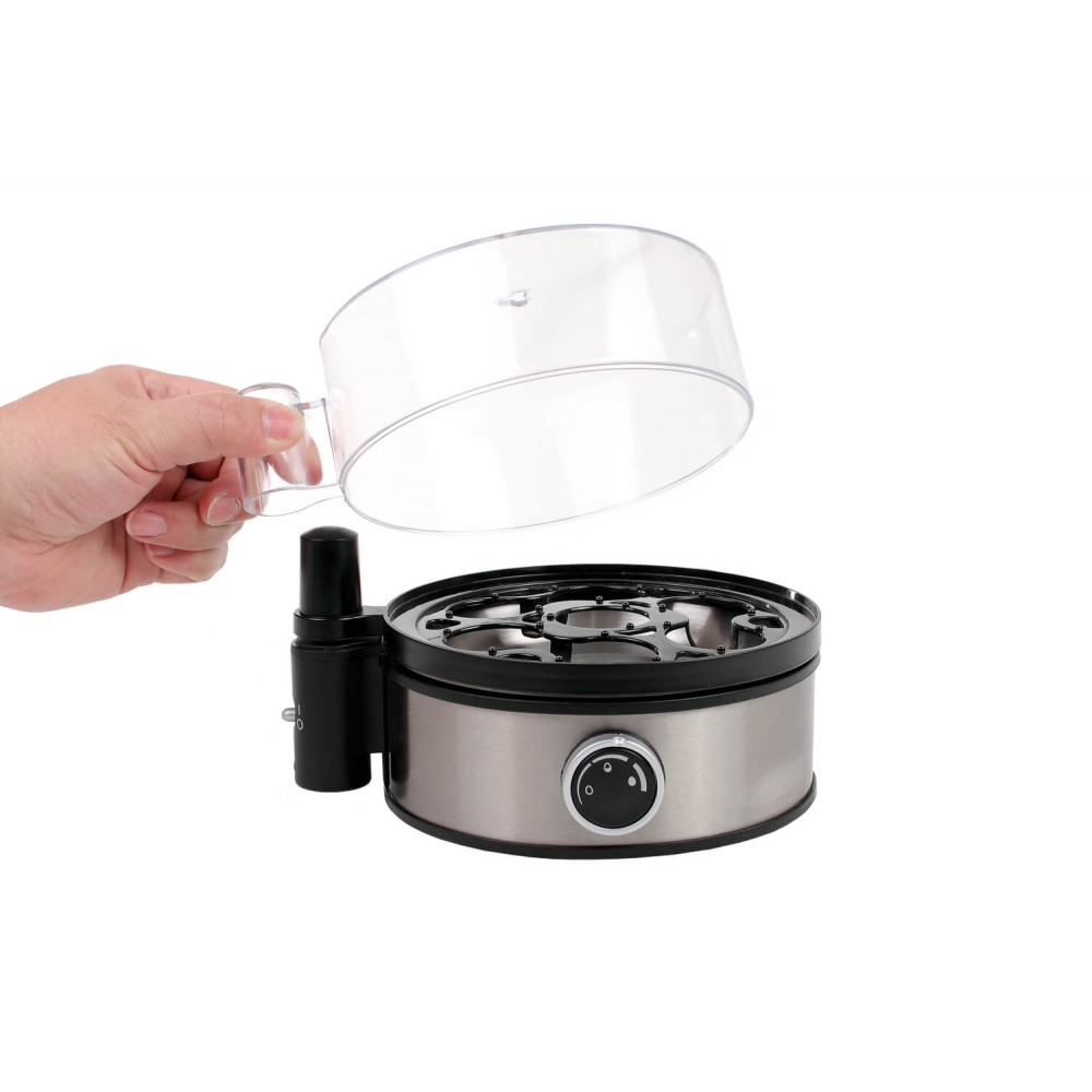Dłoń trzymająca przezroczystą pokrywę nad urządzeniem do gotowania jajek. Podstawa ze stali nierdzewnej, czarne akcenty i białe tło.
