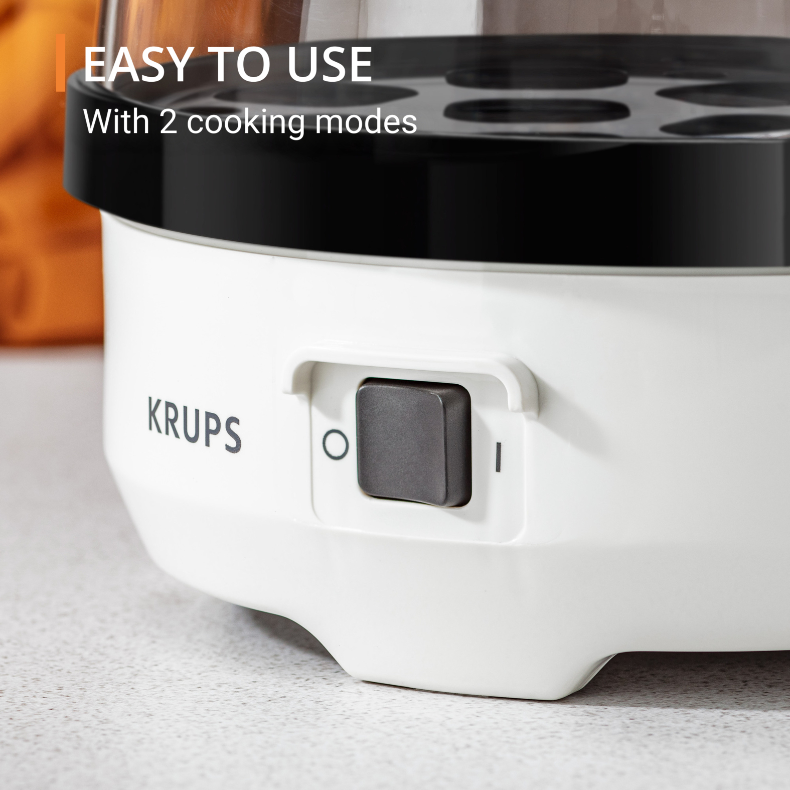 Zbliżenie białego urządzenia do gotowania jajek z czarnym wierzchem i szarym przyciskiem.