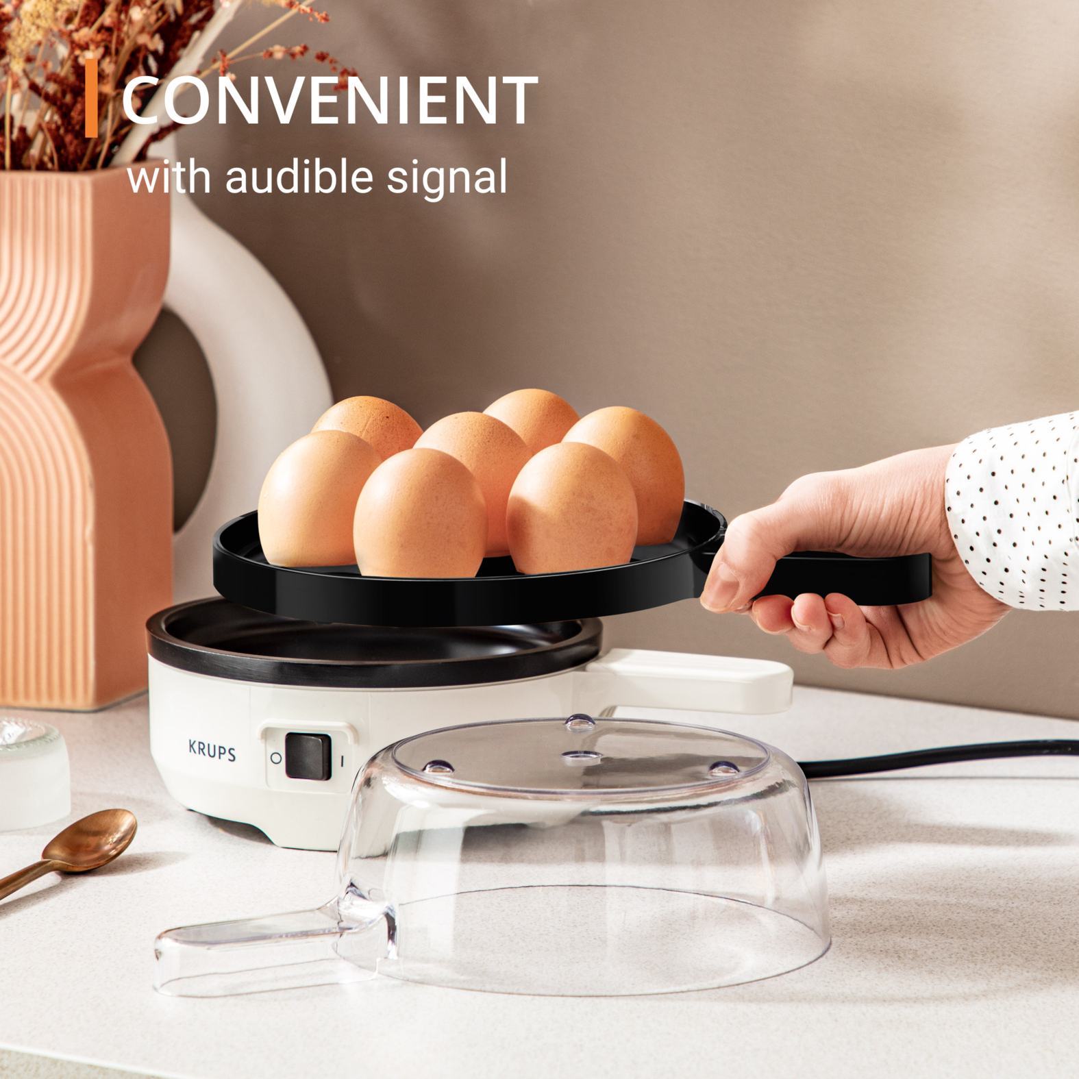 Jajowar z jajkami, pokrywką i ręką kobiety trzymającej urządzenie.