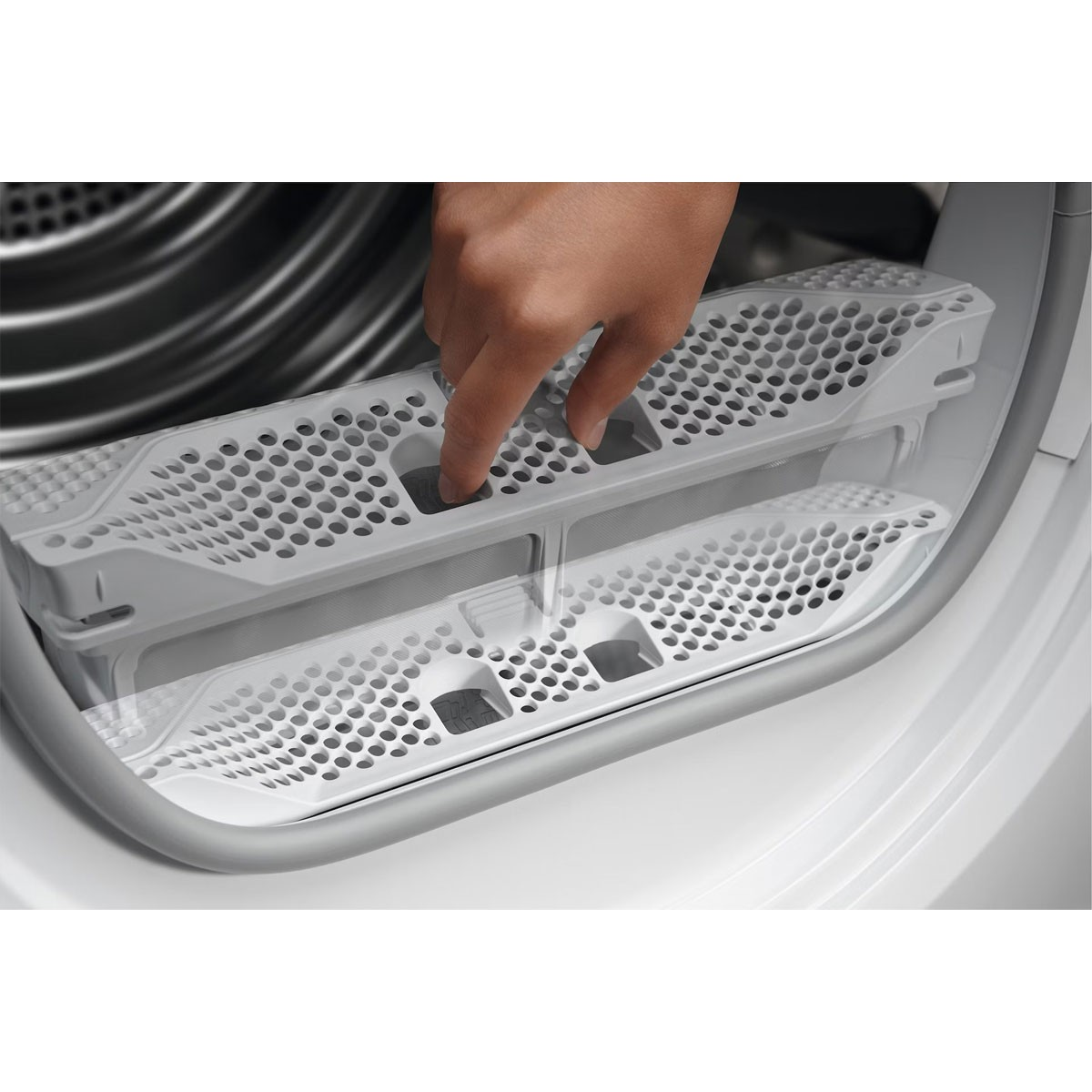 A hand inserting a filter into a white dryer machine. Close-up view, showing the grate.