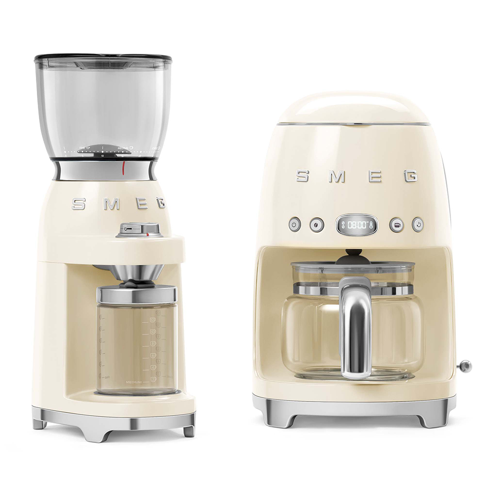 Molinillo y cafetera color marfil sobre fondo blanco. Ambos tienen la marca SMEG.
