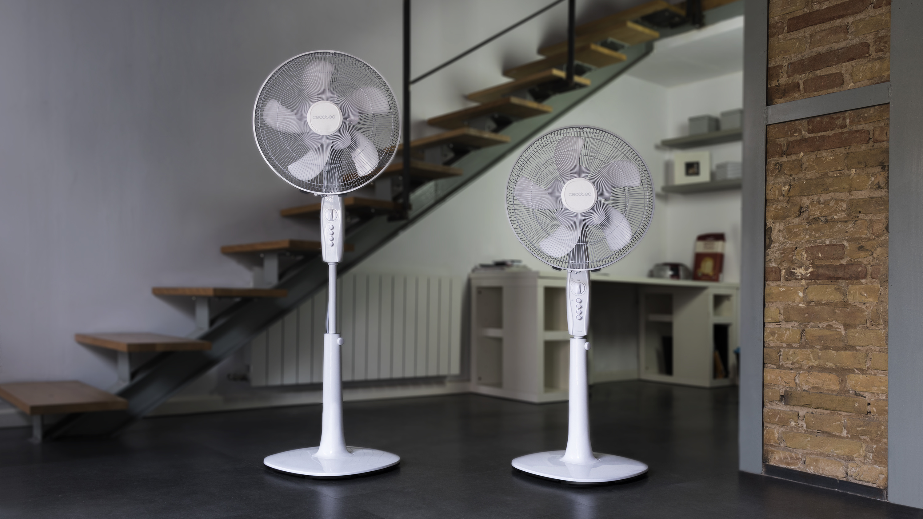 Dwa białe wentylatory stojące Cecotec w pokoju ze schodami.