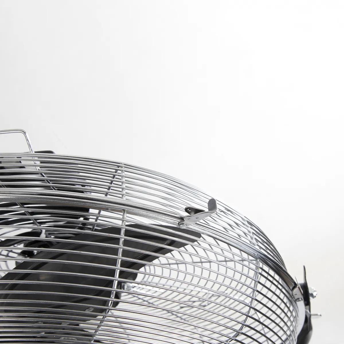 Un primer plano de un ventilador negro y plateado, contra un fondo blanco, mostrando la jaula.