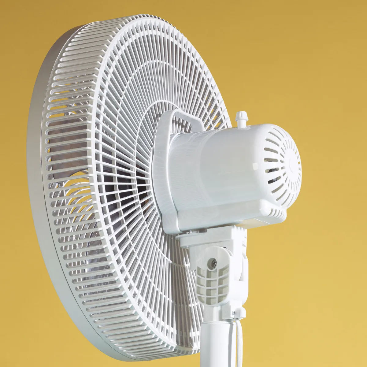 Ventilador blanco sobre fondo amarillo. Primer plano de la cabeza y el soporte del ventilador. Fondo amarillo.
