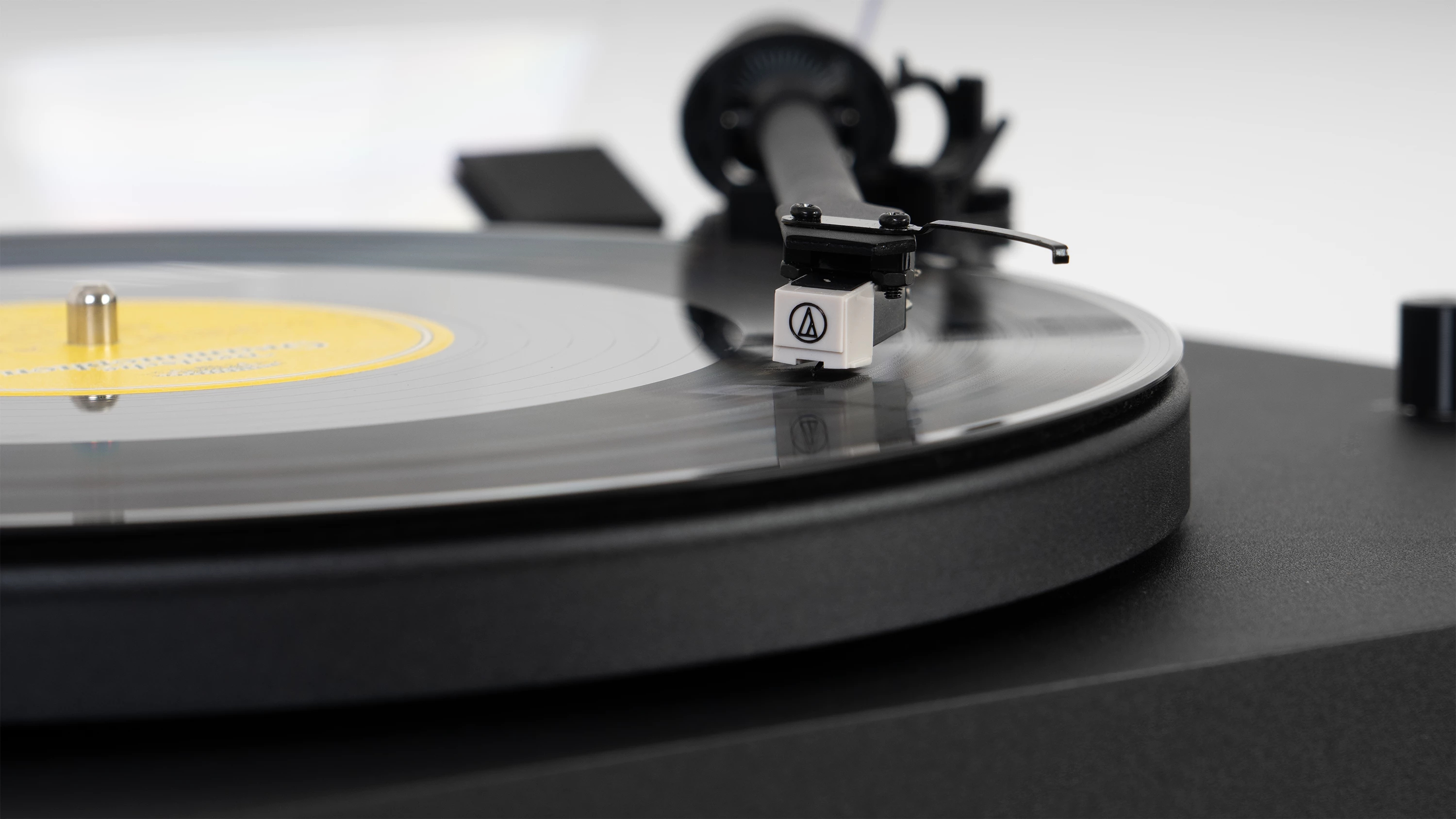 Primer plano de un tocadiscos negro con un disco girando. La aguja está sobre el disco.