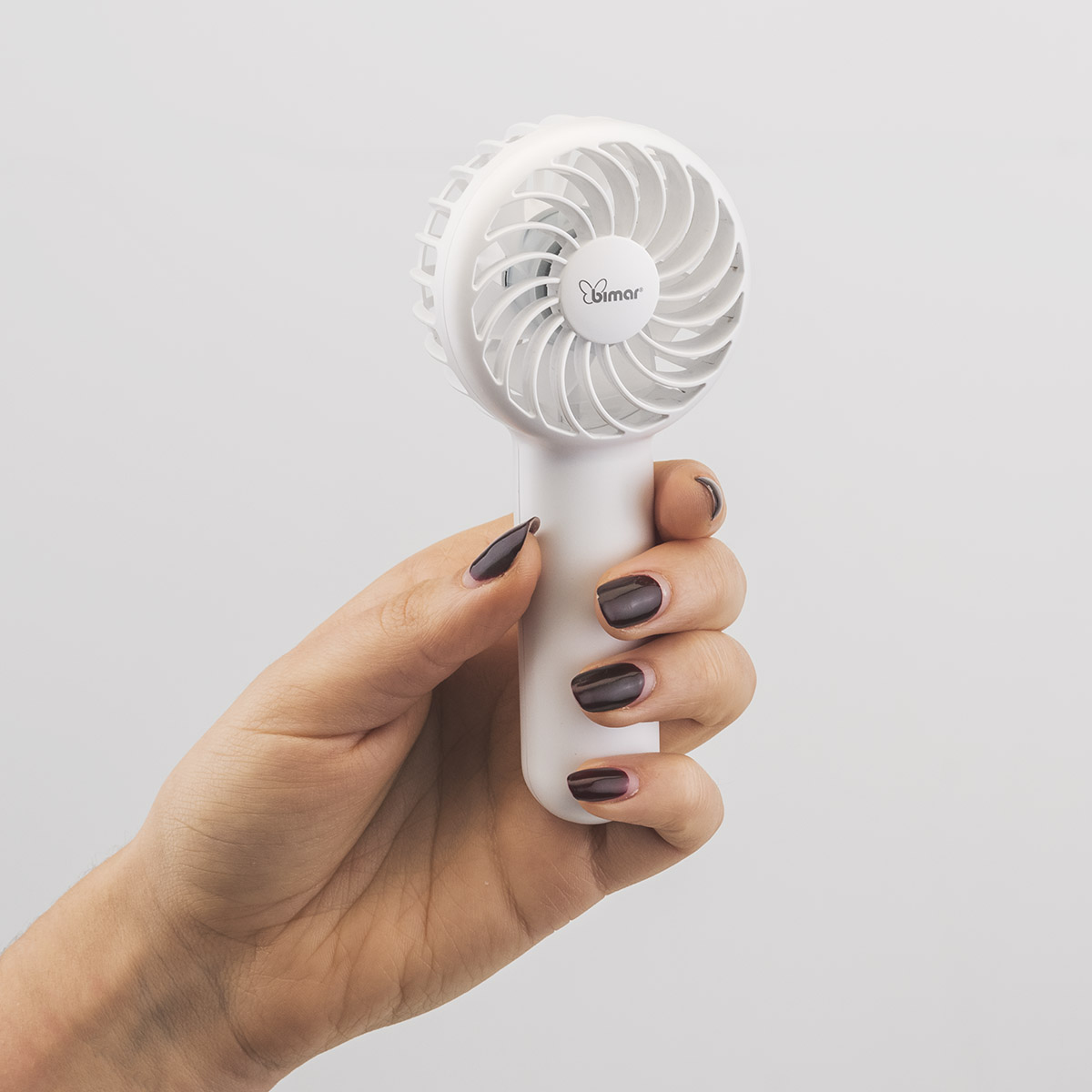 Hand houdt een witte draagbare ventilator vast. De bladen zijn zichtbaar. Witte achtergrond.