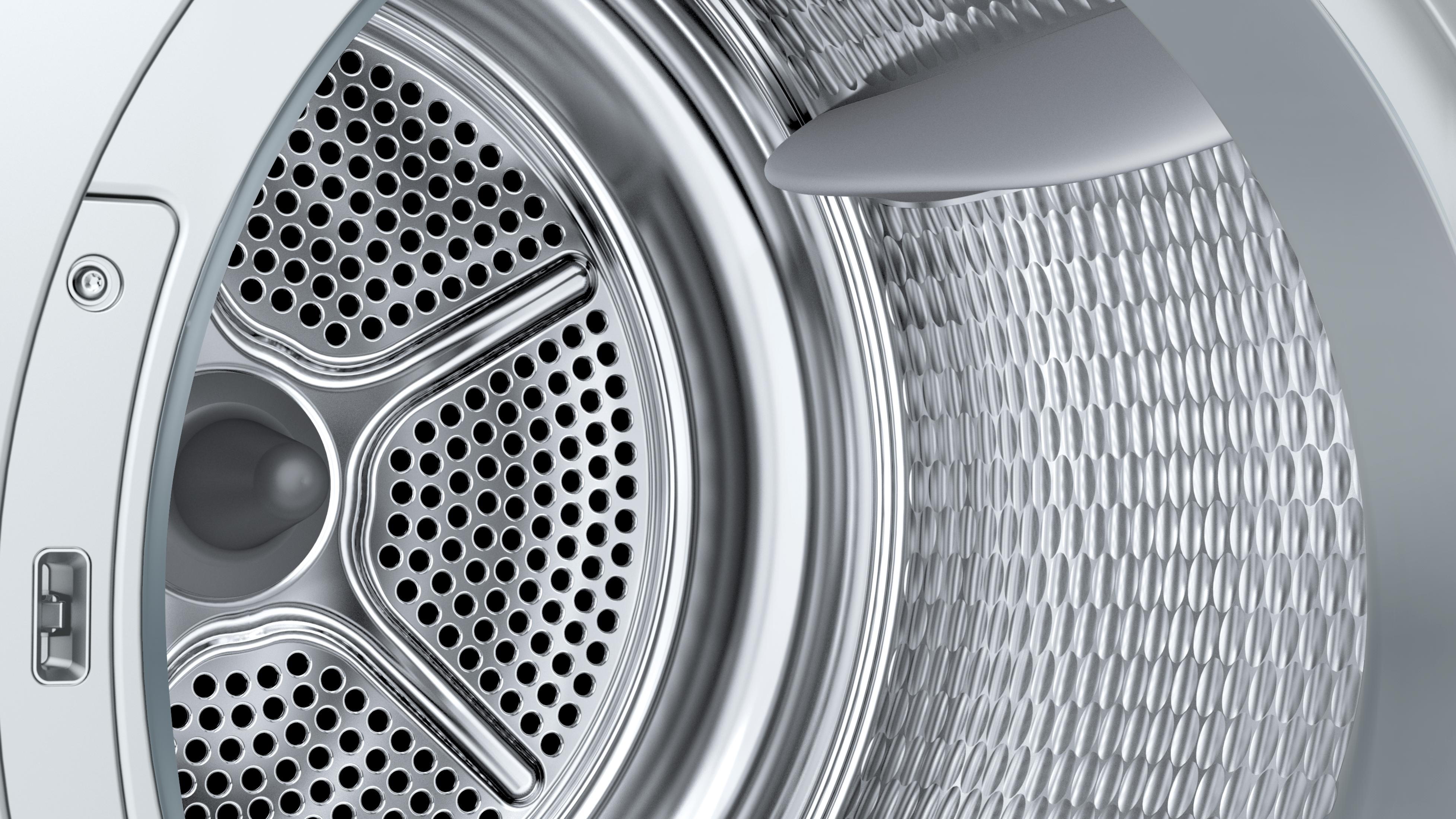 Nahaufnahme des Trommelinneren einer Waschmaschine mit Perforationen. Glänzende Metalloberfläche mit strukturierter Wand.
