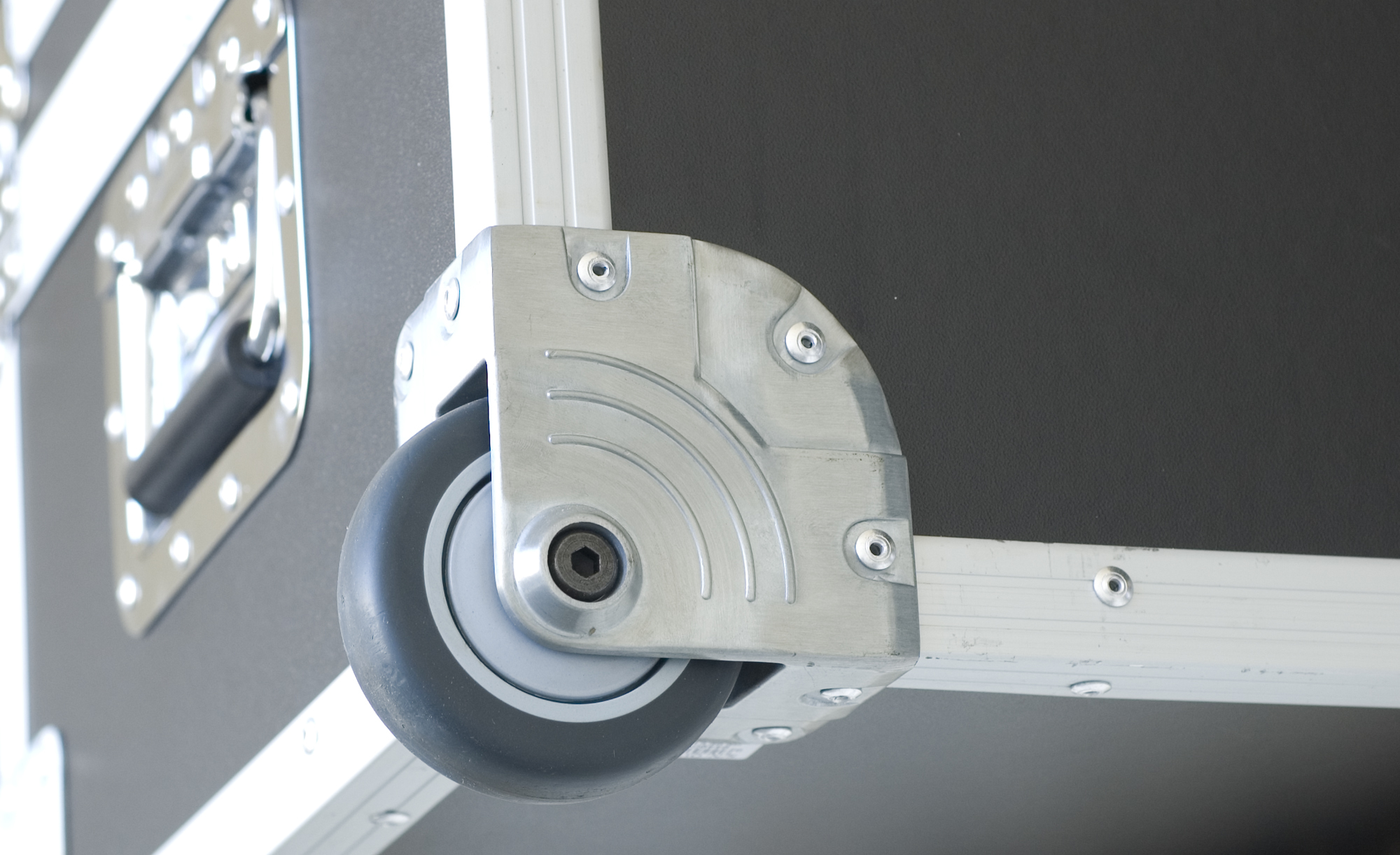 Corner of a black object with a wheel and metal frame.