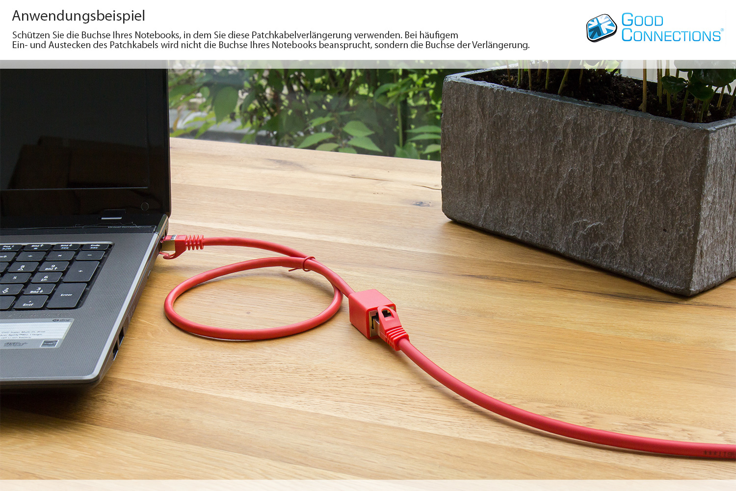 Laptop podłączony do czerwonego kabla Ethernet. Kabel na drewnianym stole.