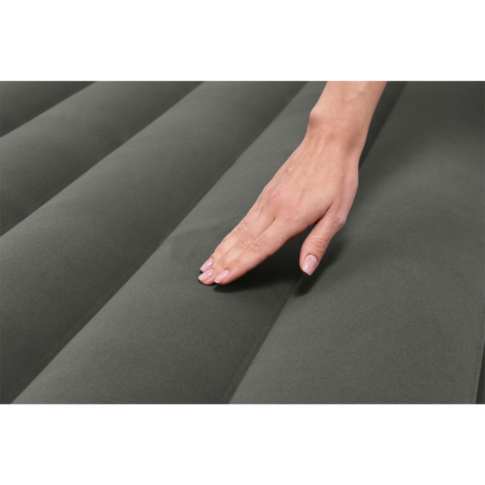 Een hand raakt een grijze, geribbelde opblaasbare matras aan. De hand heeft verzorgde nagels.