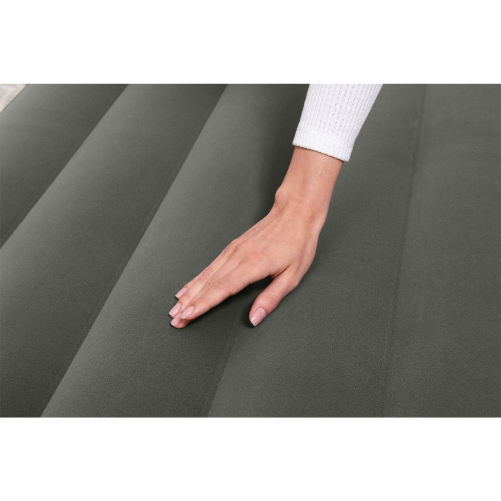 Une main touche un matelas gonflable gris. La main est près du haut du matelas gris.